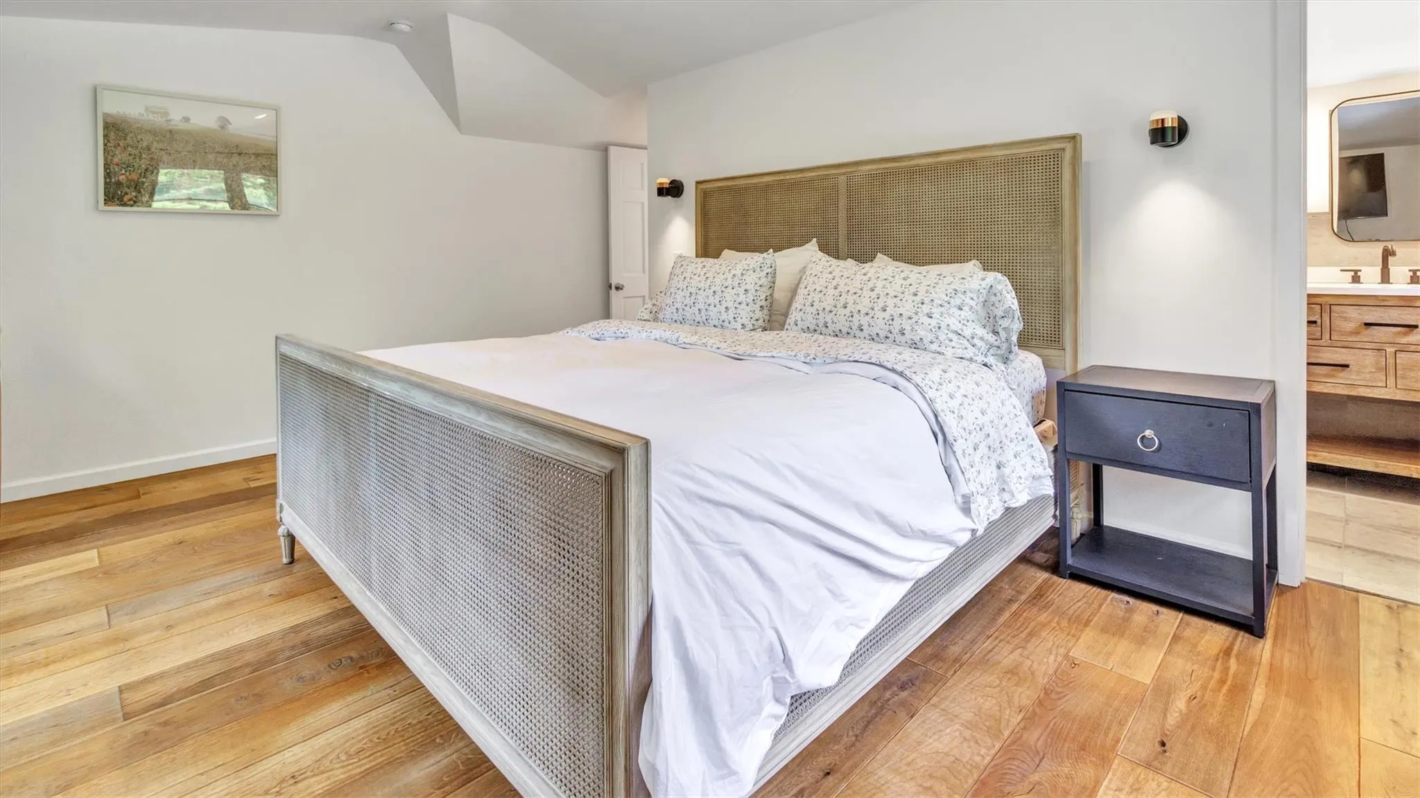 Bedroom featuring light wood-style floors, vaulted ceiling, and en-suite bathroom Bedroom featuring light wood-style floors, vaulted ceiling, and en-suite bathroom