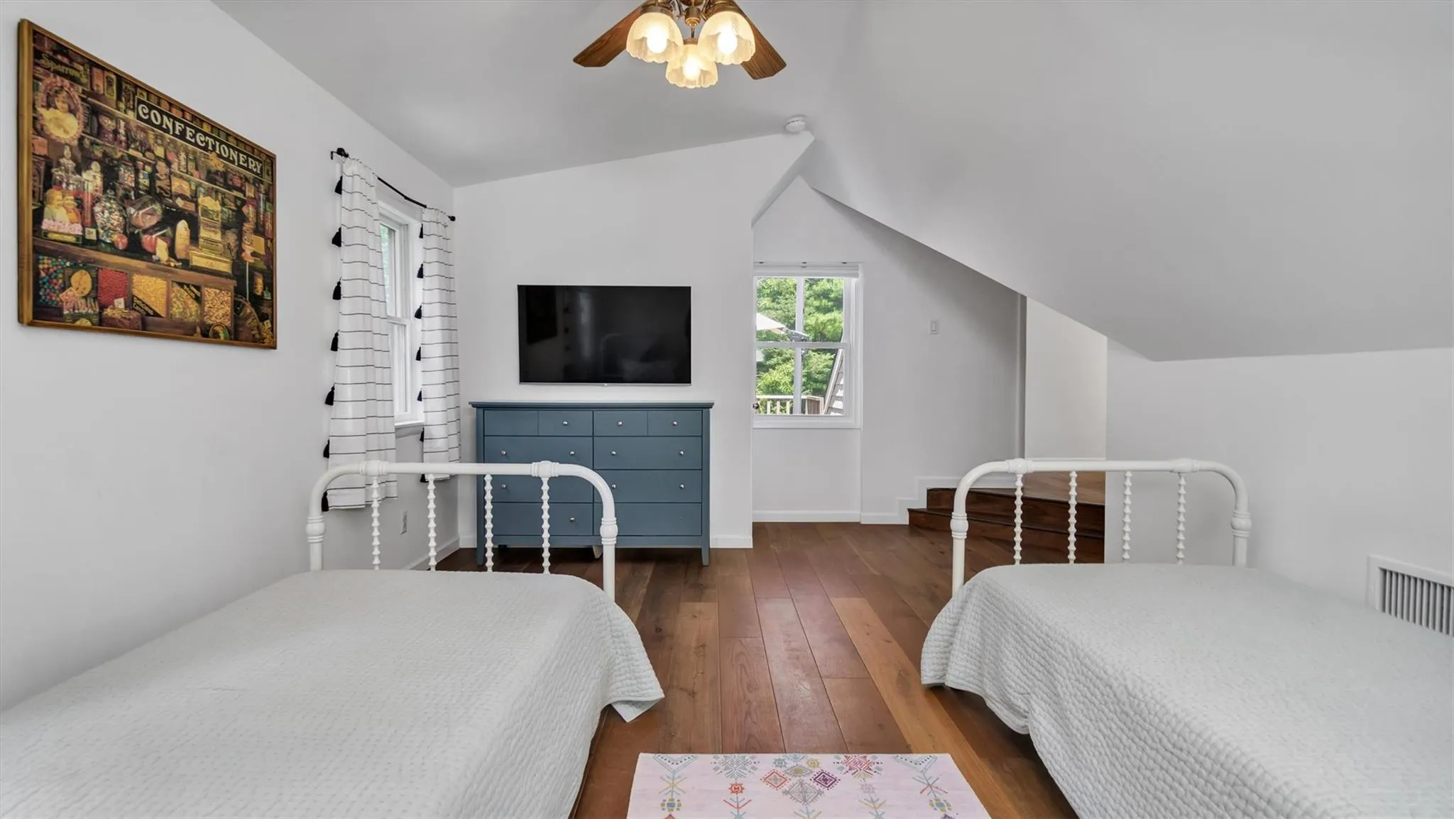 Bedroom featuring wood-type flooring, high ceiling, and ceiling fan. Bedroom featuring wood-type flooring, high ceiling, and ceiling fan.