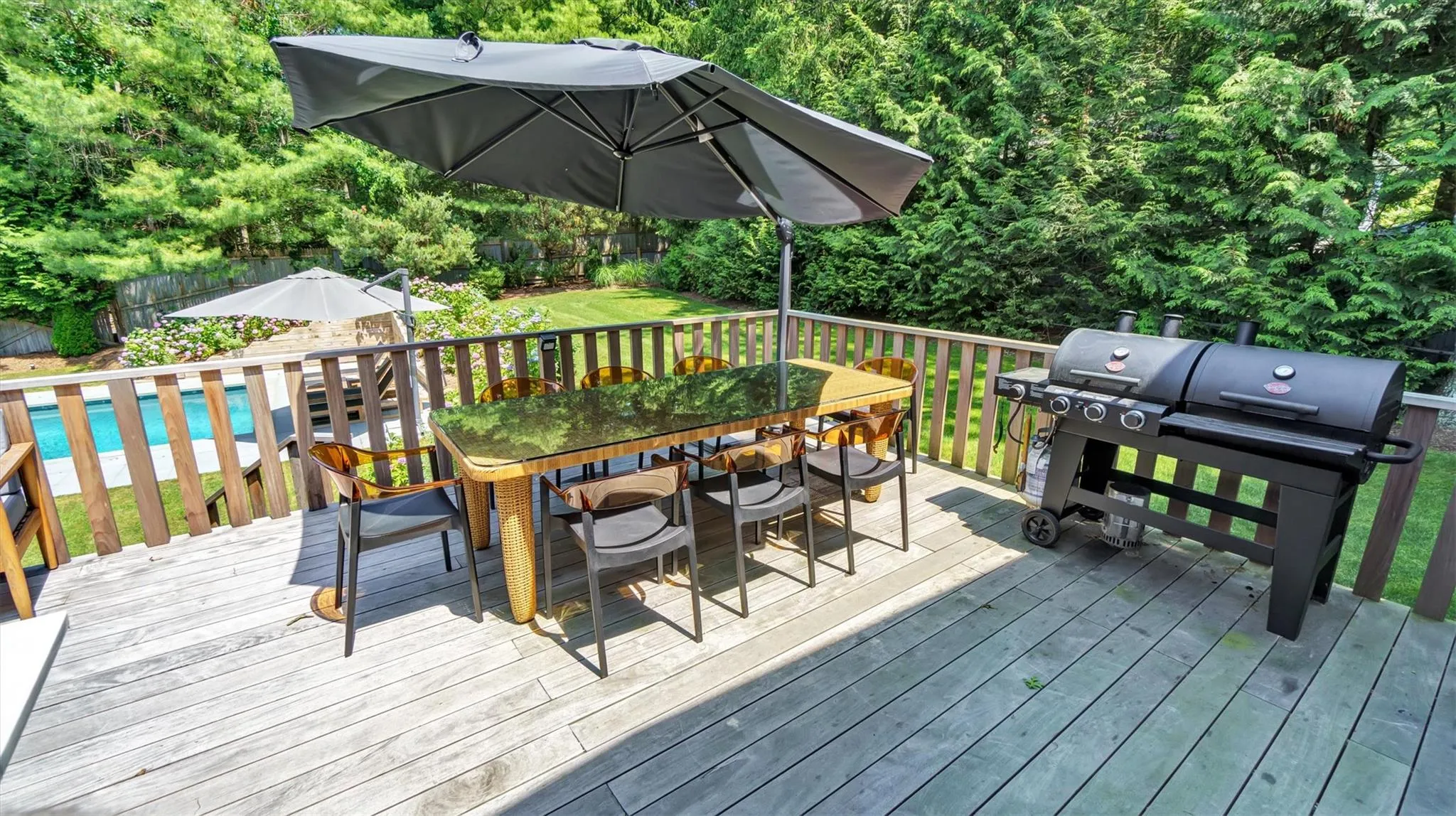 Wooden deck with a fenced backyard, outdoor dining area, and grill. Wooden deck with a fenced backyard, outdoor dining area, and grill.