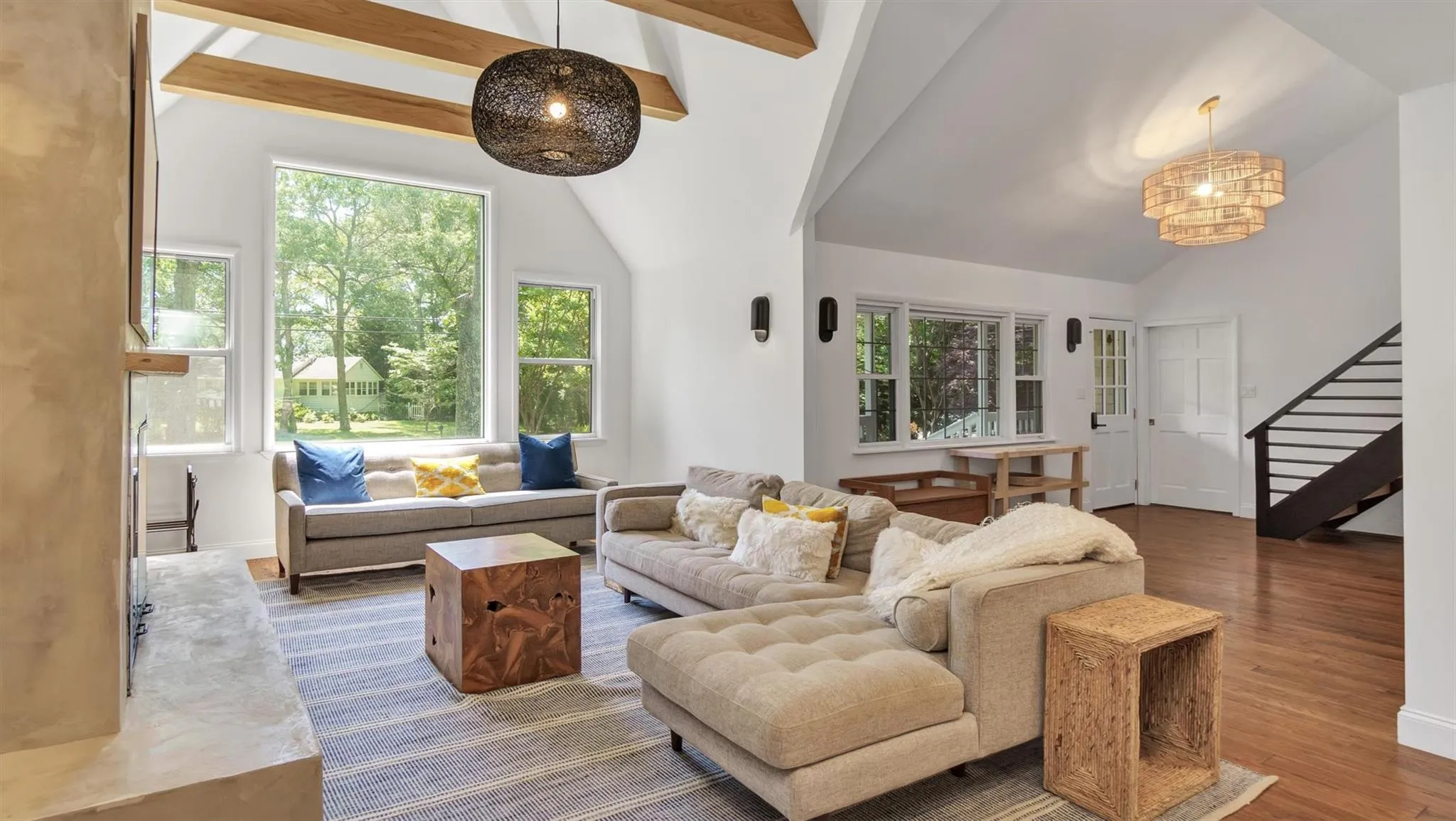 Living area featuring stairway, wood finished floors, high ceiling, and a chandelier. Living area featuring stairway, wood finished floors, high ceiling, and a chandelier.