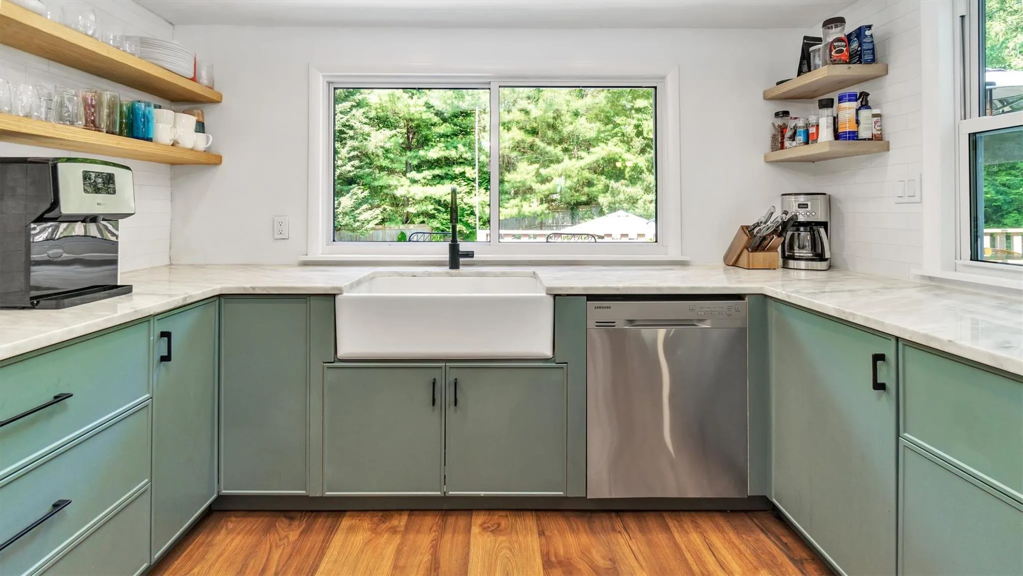 Kitchen with green cabinets, stainless steel dishwasher, and open shelves. Kitchen with green cabinets, stainless steel dishwasher, and open shelves.