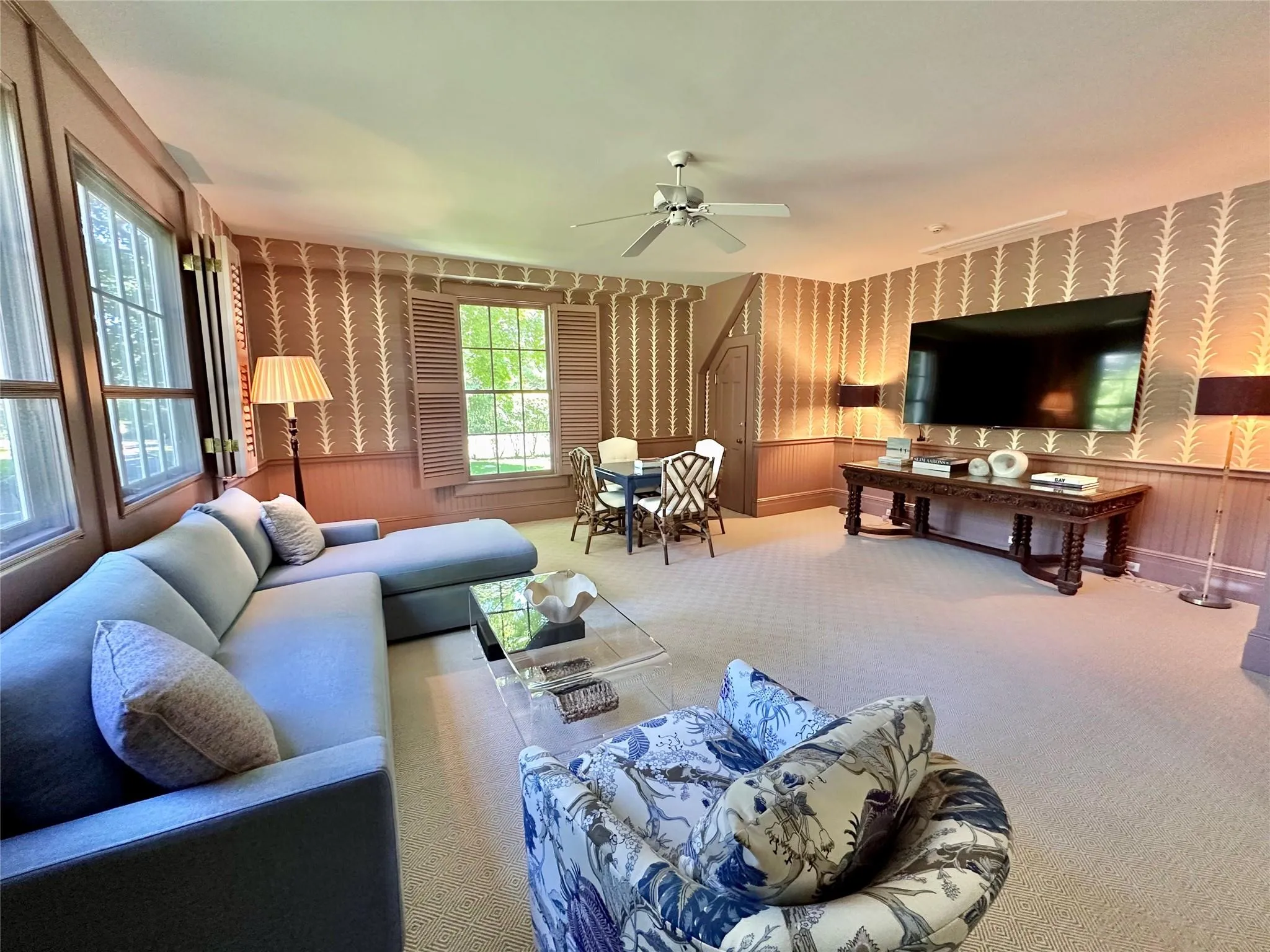 Living room featuring wallpapered walls, ceiling fan, carpet, and wainscoting Living room featuring wallpapered walls, ceiling fan, carpet, and wainscoting