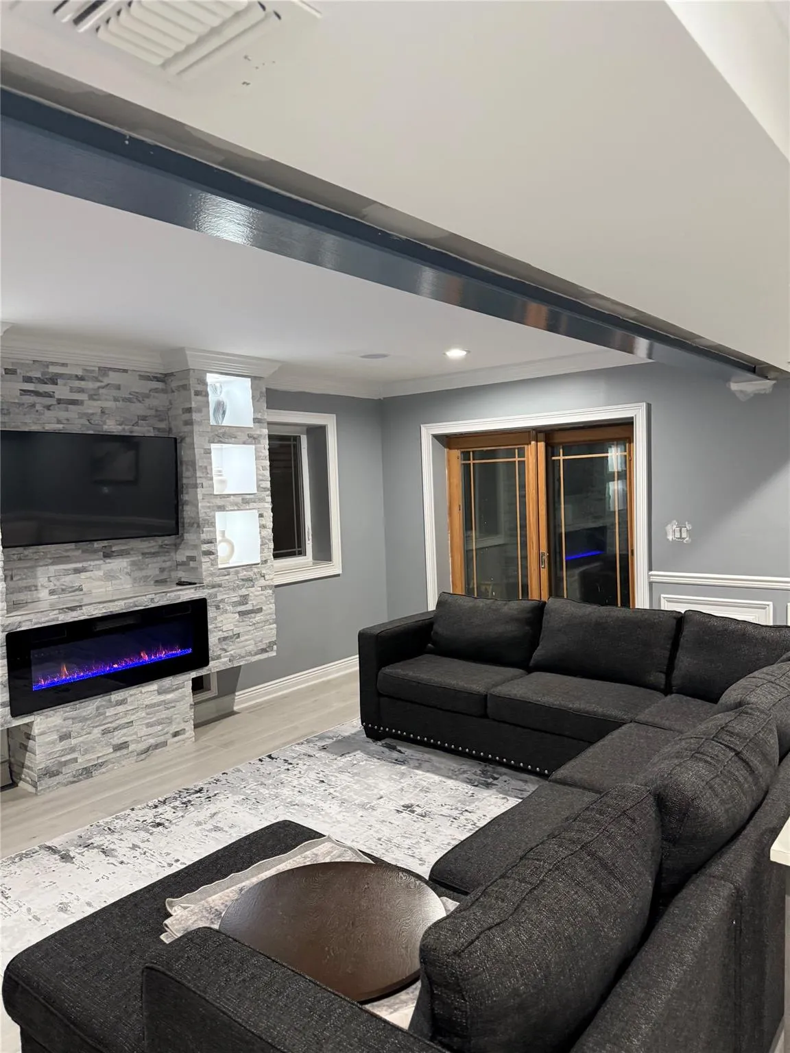 Living room with a large fireplace, crown molding, and hardwood / wood-style floors Living room with a large fireplace, crown molding, and hardwood / wood-style floors
