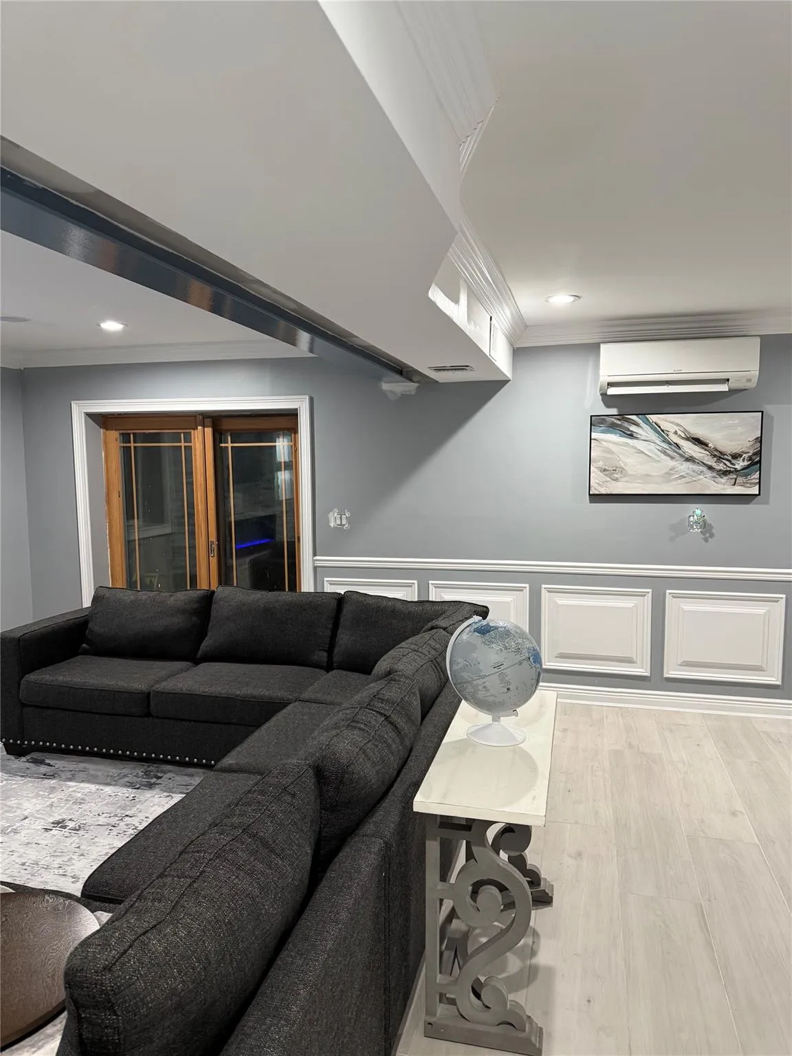Living room with light wood-type flooring, a wall mounted AC, and crown molding Living room with light wood-type flooring, a wall mounted AC, and crown molding