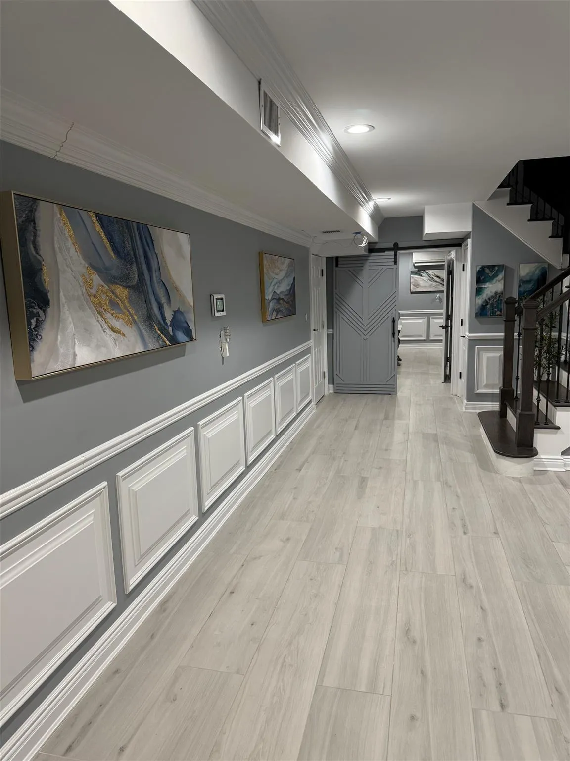 Hallway with light hardwood / wood-style floors and crown molding Hallway with light hardwood / wood-style floors and crown molding