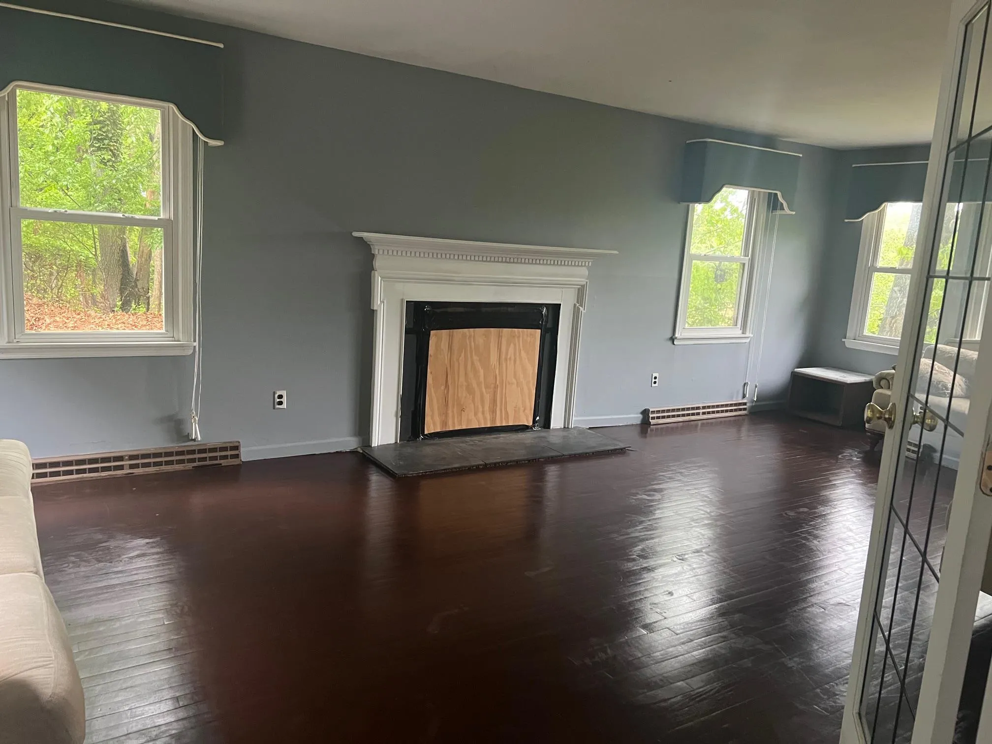Unfurnished living room featuring baseboard heating, hardwood / wood-style floors, a fireplace with raised hearth, and baseboards Unfurnished living room featuring baseboard heating, hardwood / wood-style floors, a fireplace with raised hearth, and baseboards