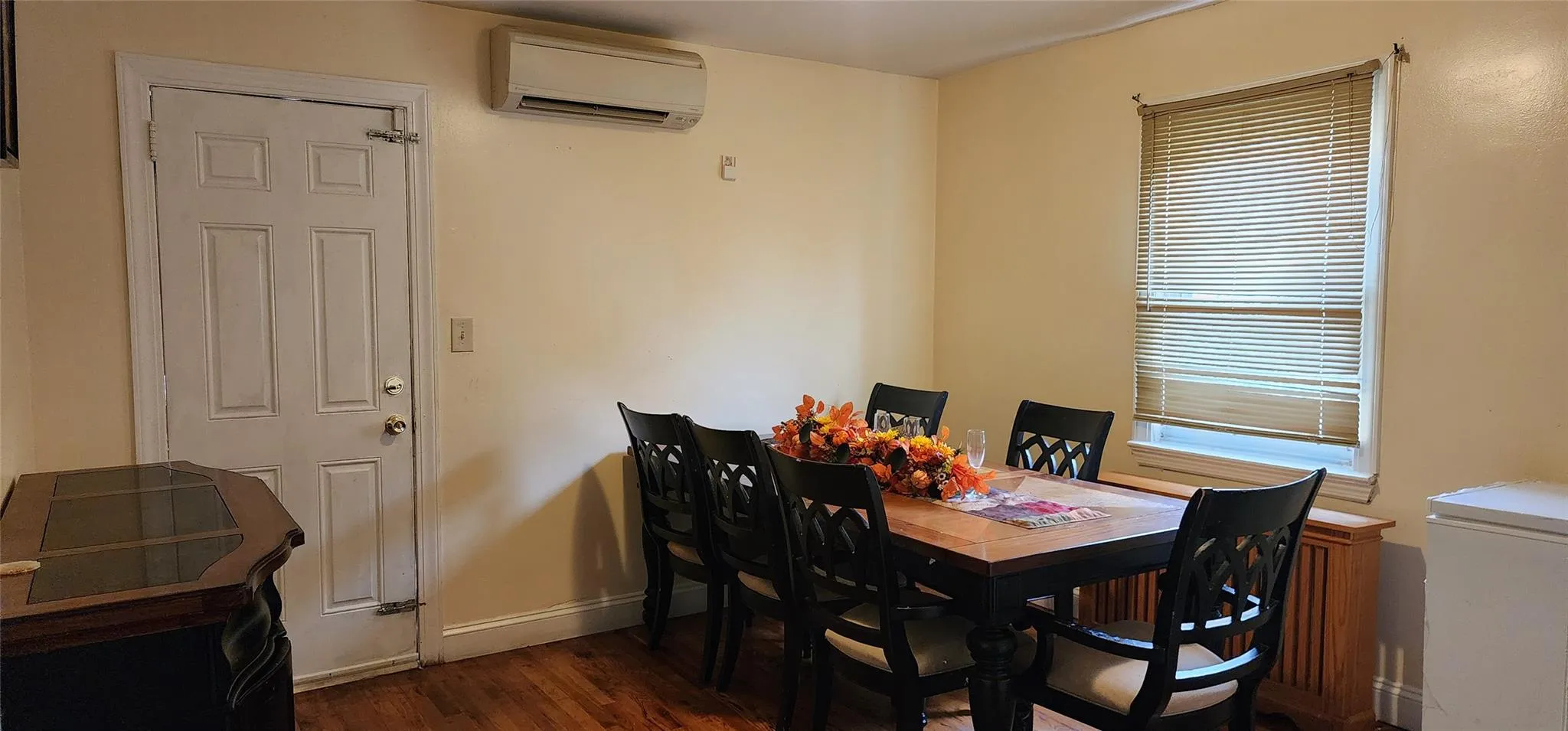 Dining area with dark wood finished floors and an AC wall unit Dining area with dark wood finished floors and an AC wall unit