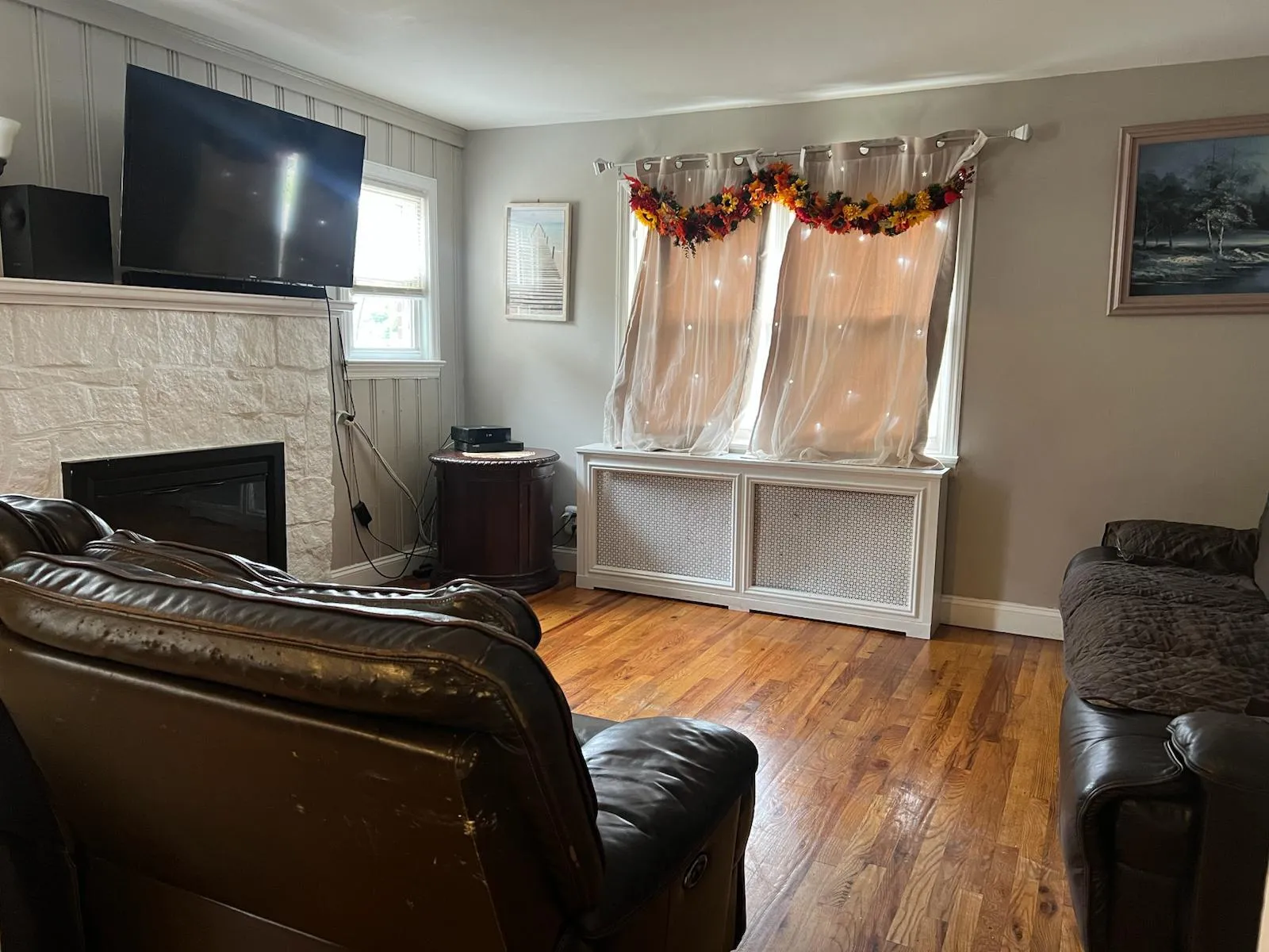 Living area with wood finished floors, radiator heating unit, and a fireplace Living area with wood finished floors, radiator heating unit, and a fireplace