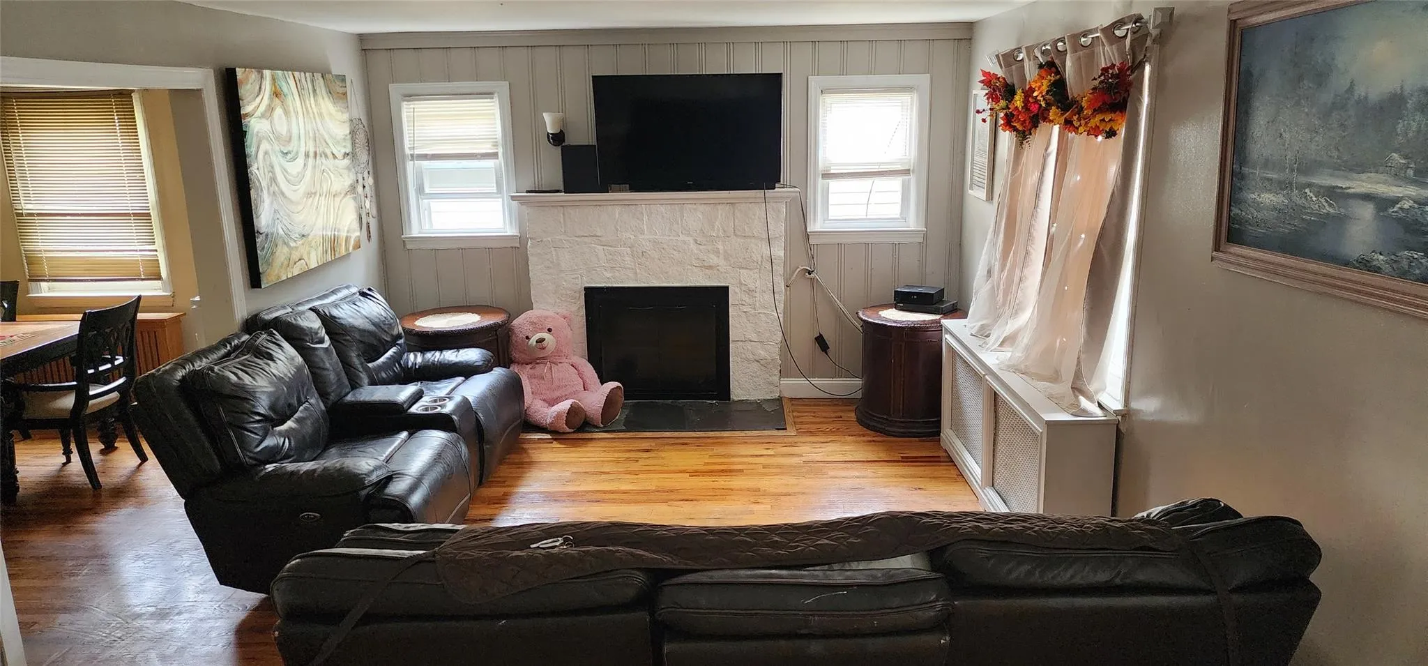 Living room featuring a fireplace with flush hearth, healthy amount of natural light, wood finished floors, and radiator Living room featuring a fireplace with flush hearth, healthy amount of natural light, wood finished floors, and radiator