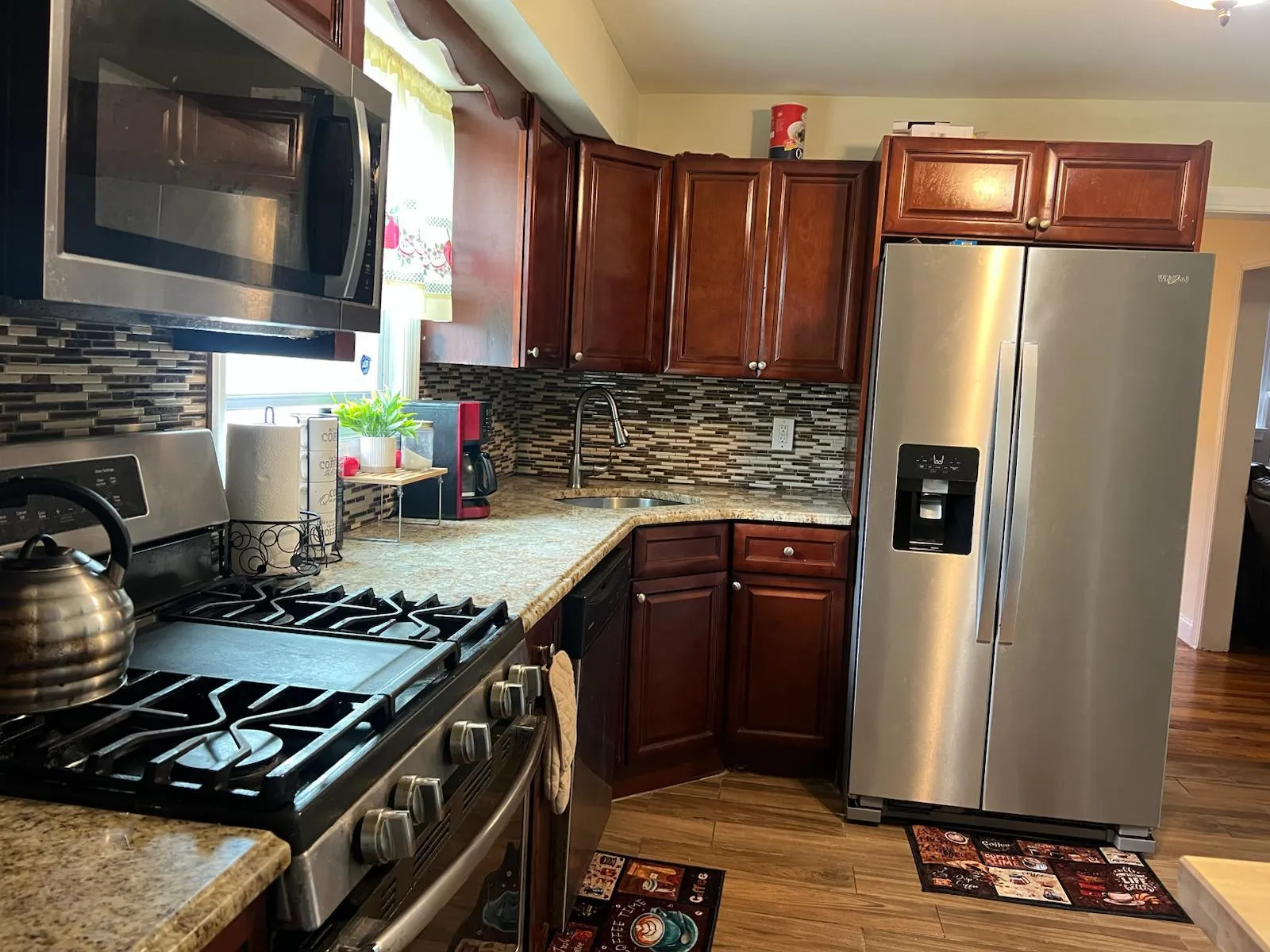 Kitchen with stainless steel appliances, tasteful backsplash, light stone countertops, and dark wood-style floors Kitchen with stainless steel appliances, tasteful backsplash, light stone countertops, and dark wood-style floors