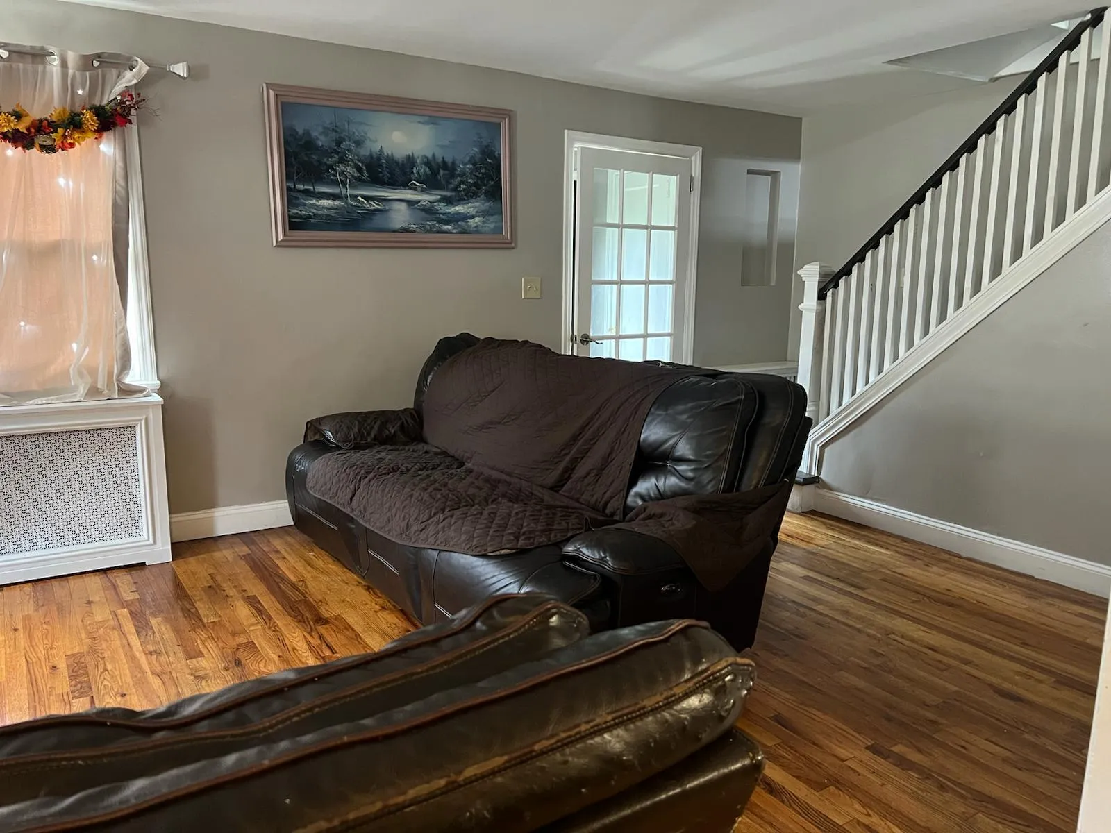 Living area with radiator heating unit, wood finished floors, and stairs Living area with radiator heating unit, wood finished floors, and stairs