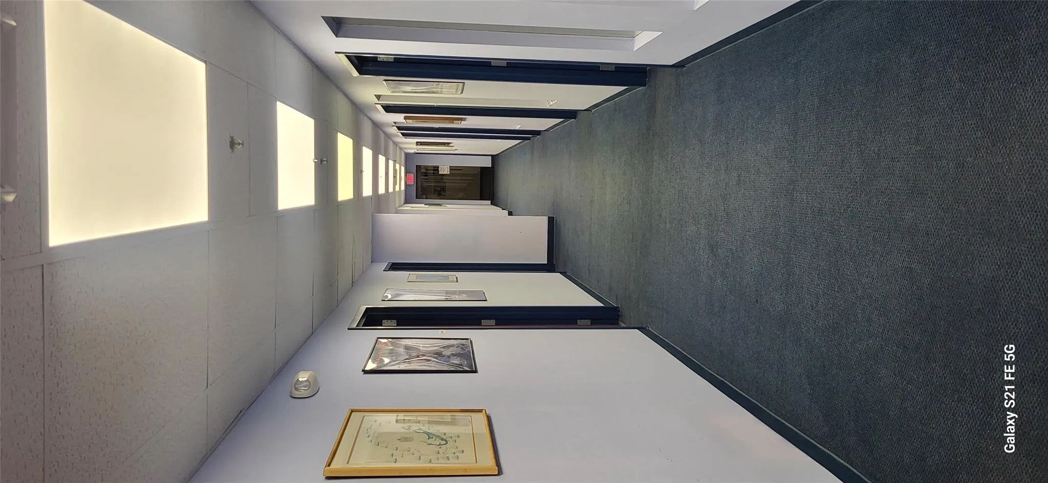 Hall featuring dark colored carpet and a paneled ceiling Hall featuring dark colored carpet and a paneled ceiling