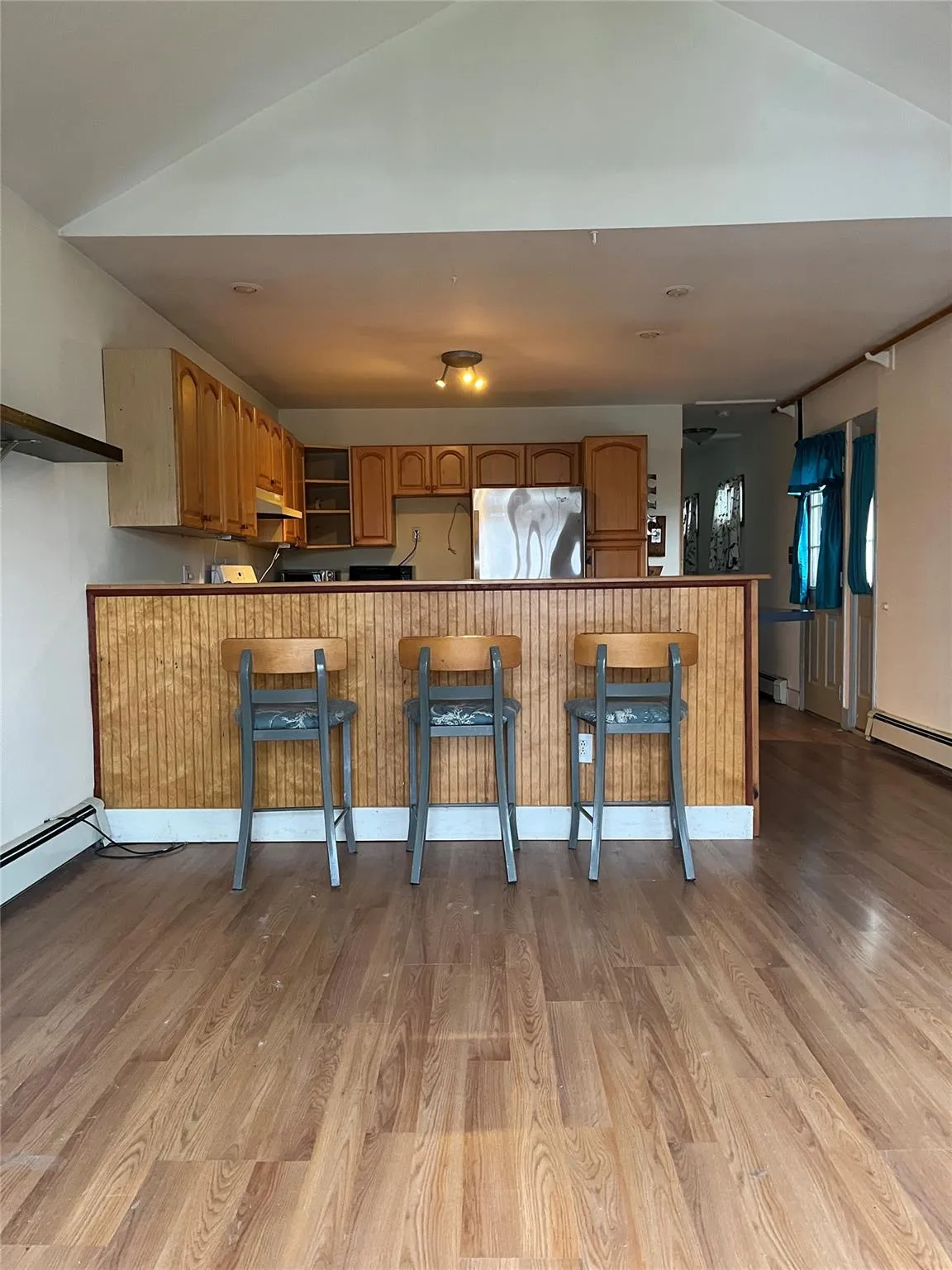 Kitchen with stainless steel refrigerator, kitchen peninsula, light hardwood / wood-style flooring, and a breakfast bar area Kitchen with stainless steel refrigerator, kitchen peninsula, light hardwood / wood-style flooring, and a breakfast bar area