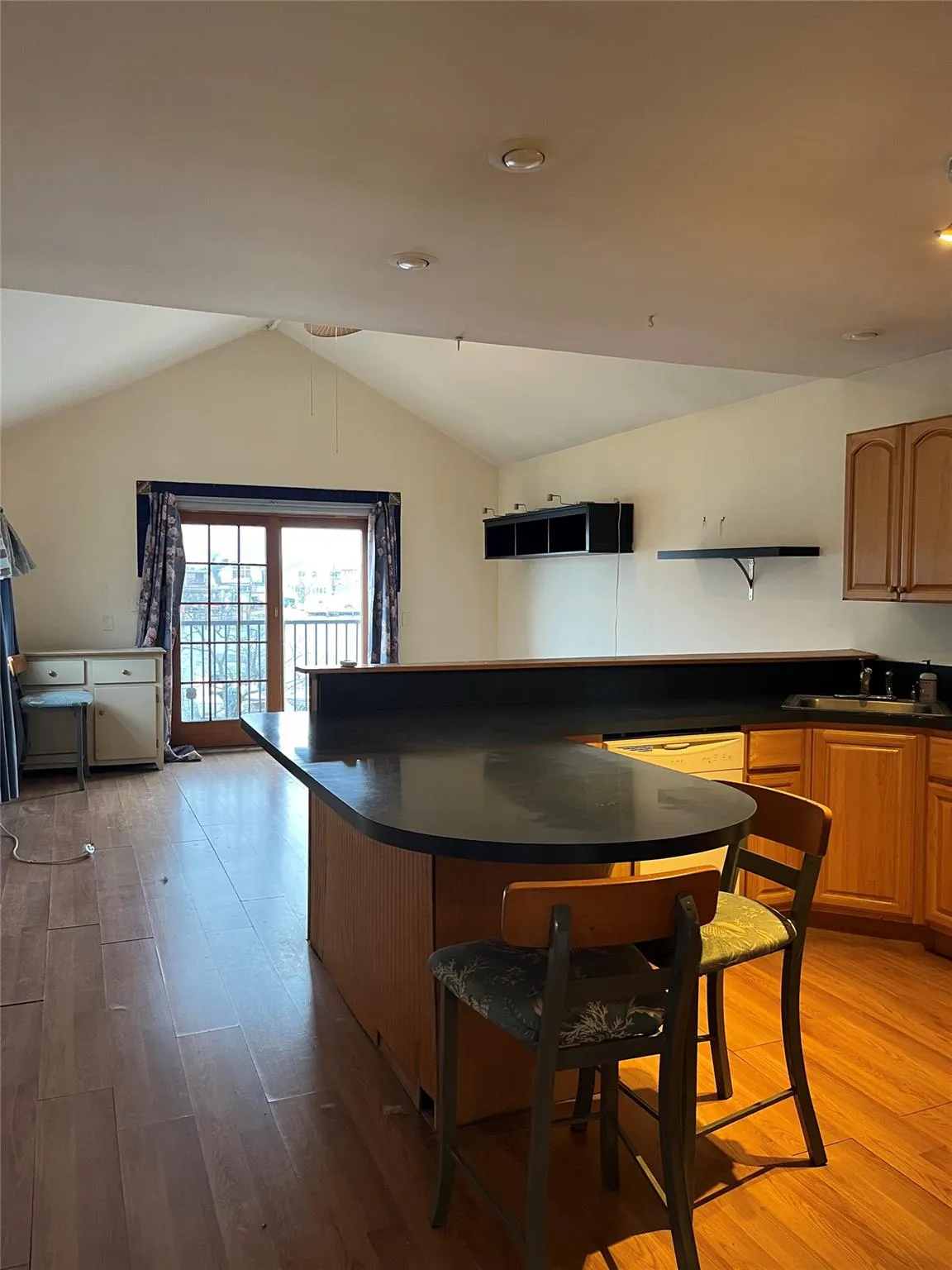 Kitchen featuring a kitchen breakfast bar, light hardwood / wood-style flooring, vaulted ceiling, and sink Kitchen featuring a kitchen breakfast bar, light hardwood / wood-style flooring, vaulted ceiling, and sink