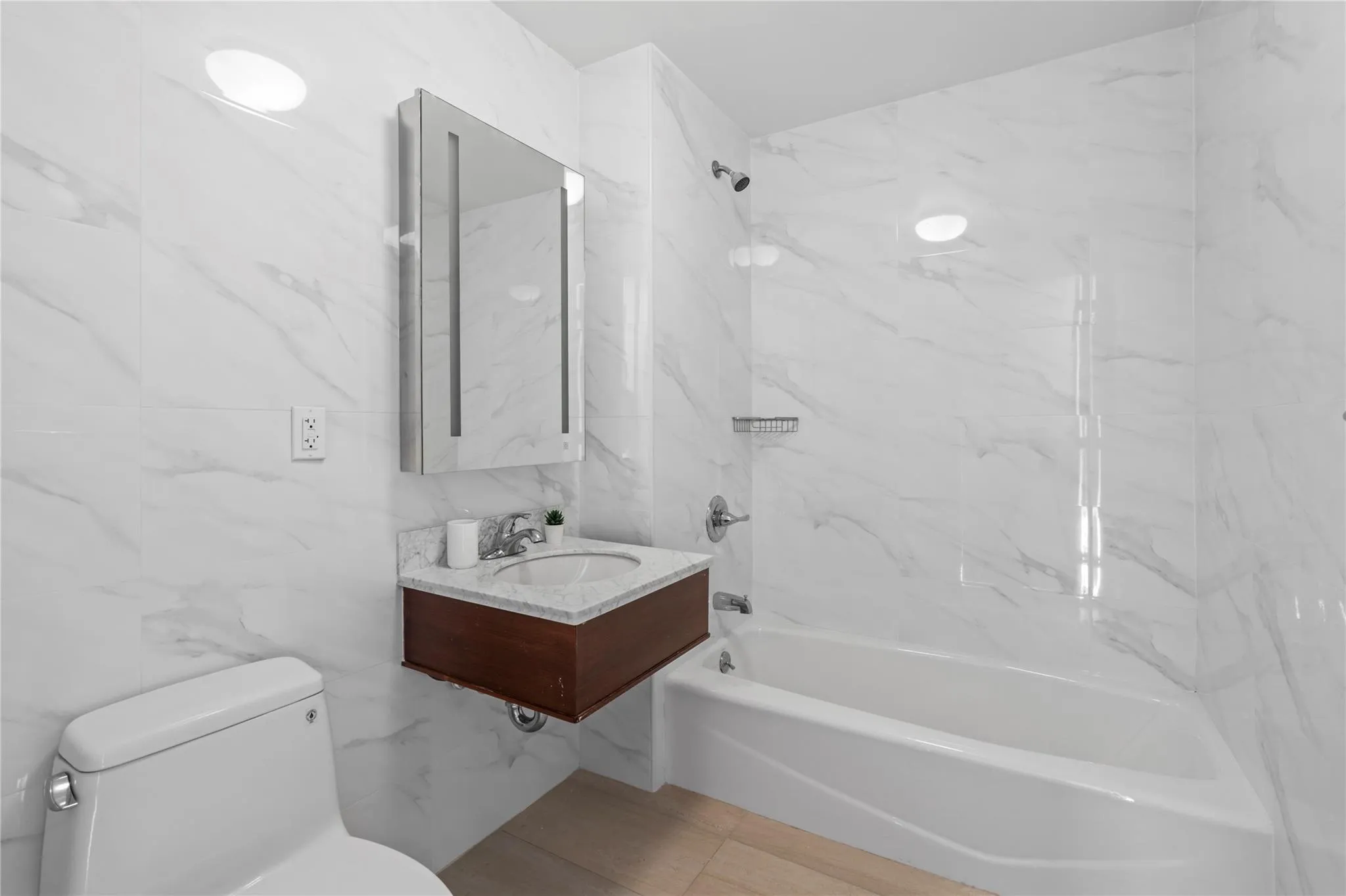 Full bathroom with tile walls, toilet, tiled shower / bath, and sink Full bathroom with tile walls, toilet, tiled shower / bath, and sink