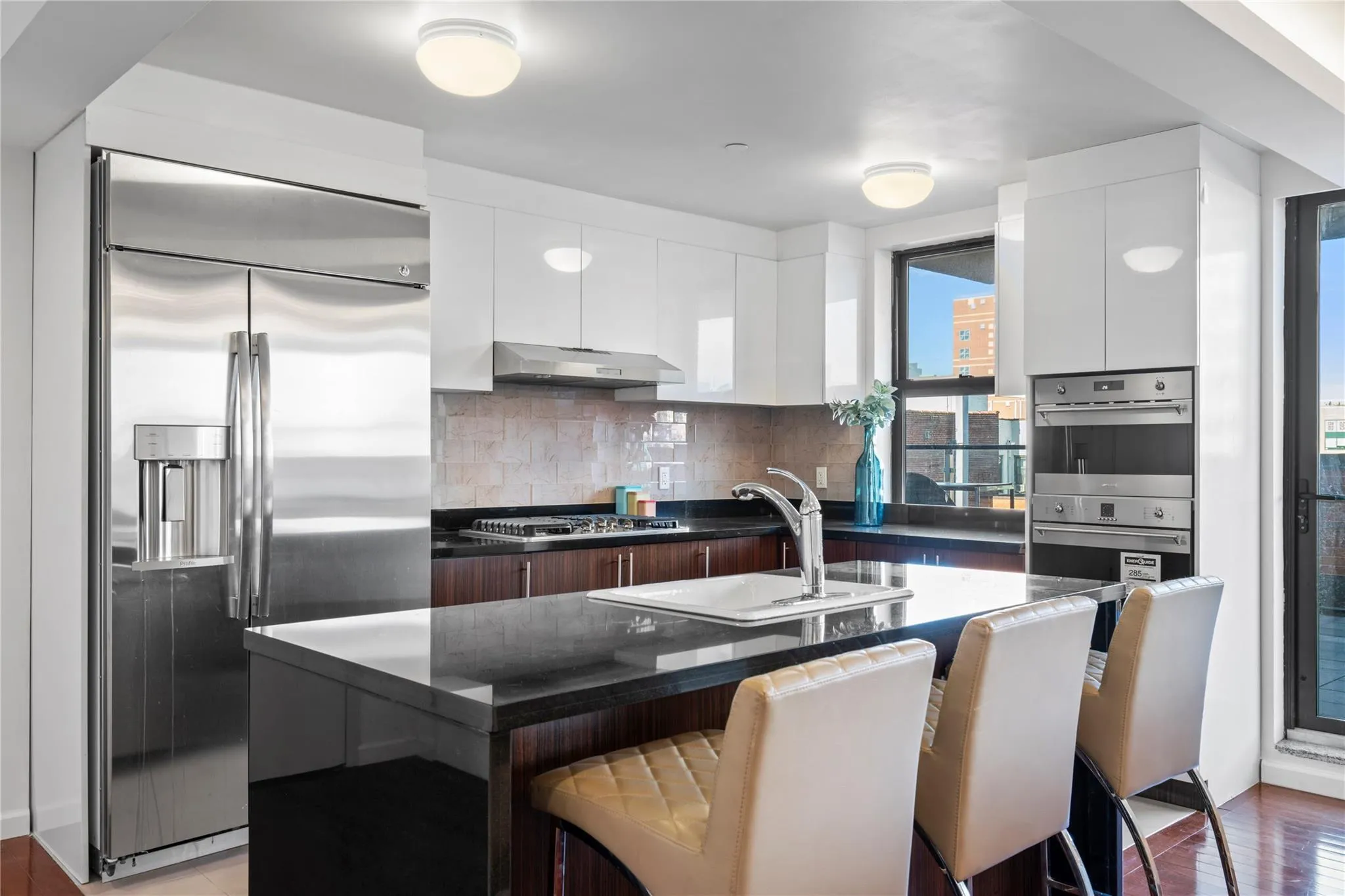 Kitchen with a kitchen island with sink, white cabinets, sink, appliances with stainless steel finishes, and extractor fan Kitchen with a kitchen island with sink, white cabinets, sink, appliances with stainless steel finishes, and extractor fan