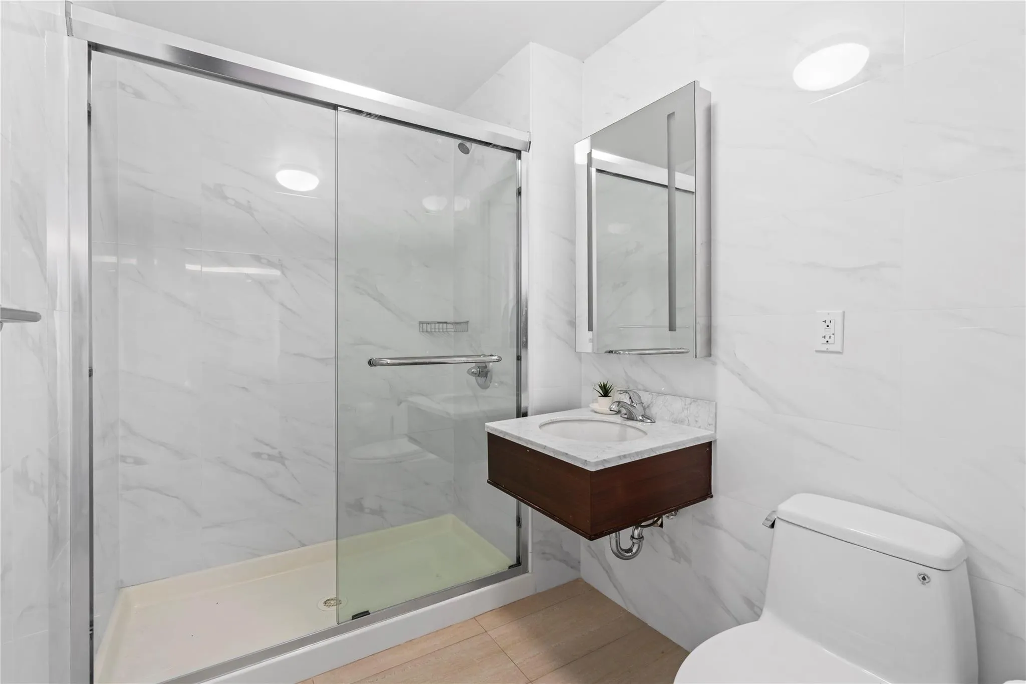 Bathroom featuring tile walls, toilet, walk in shower, and sink Bathroom featuring tile walls, toilet, walk in shower, and sink