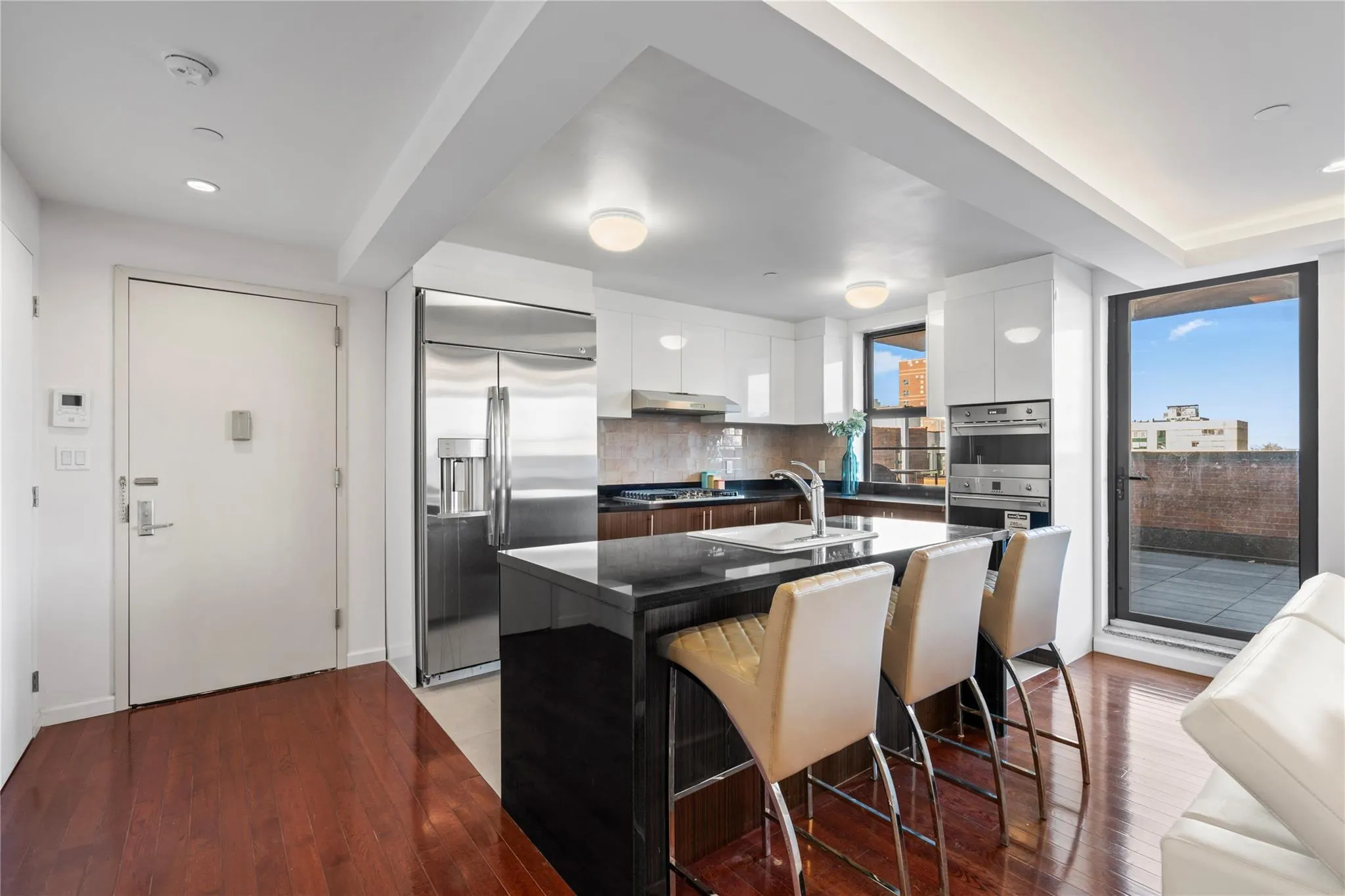 Kitchen featuring stainless steel appliances, plenty of natural light, a breakfast bar area, a kitchen island with sink, and white cabinets Kitchen featuring stainless steel appliances, plenty of natural light, a breakfast bar area, a kitchen island with sink, and white cabinets