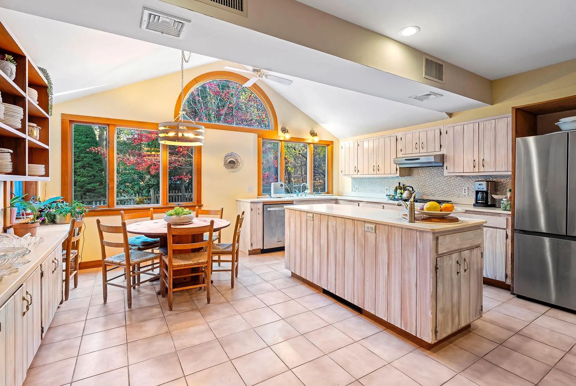 Kitchen with light countertops, open shelves, lofted ceiling, stainless steel appliances, and an island with sink Kitchen with light countertops, open shelves, lofted ceiling, stainless steel appliances, and an island with sink