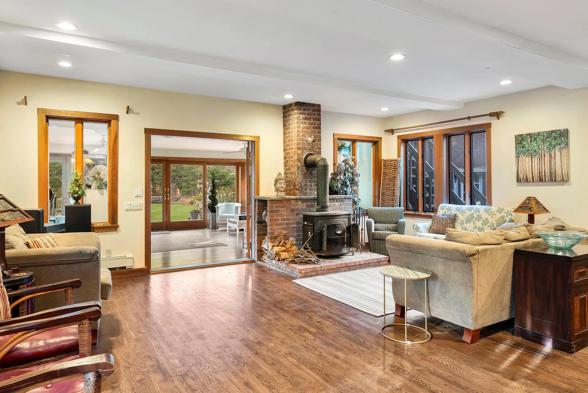 Living room featuring a wood stove, wood finished floors, recessed lighting, a baseboard radiator, and beam ceiling Living room featuring a wood stove, wood finished floors, recessed lighting, a baseboard radiator, and beam ceiling