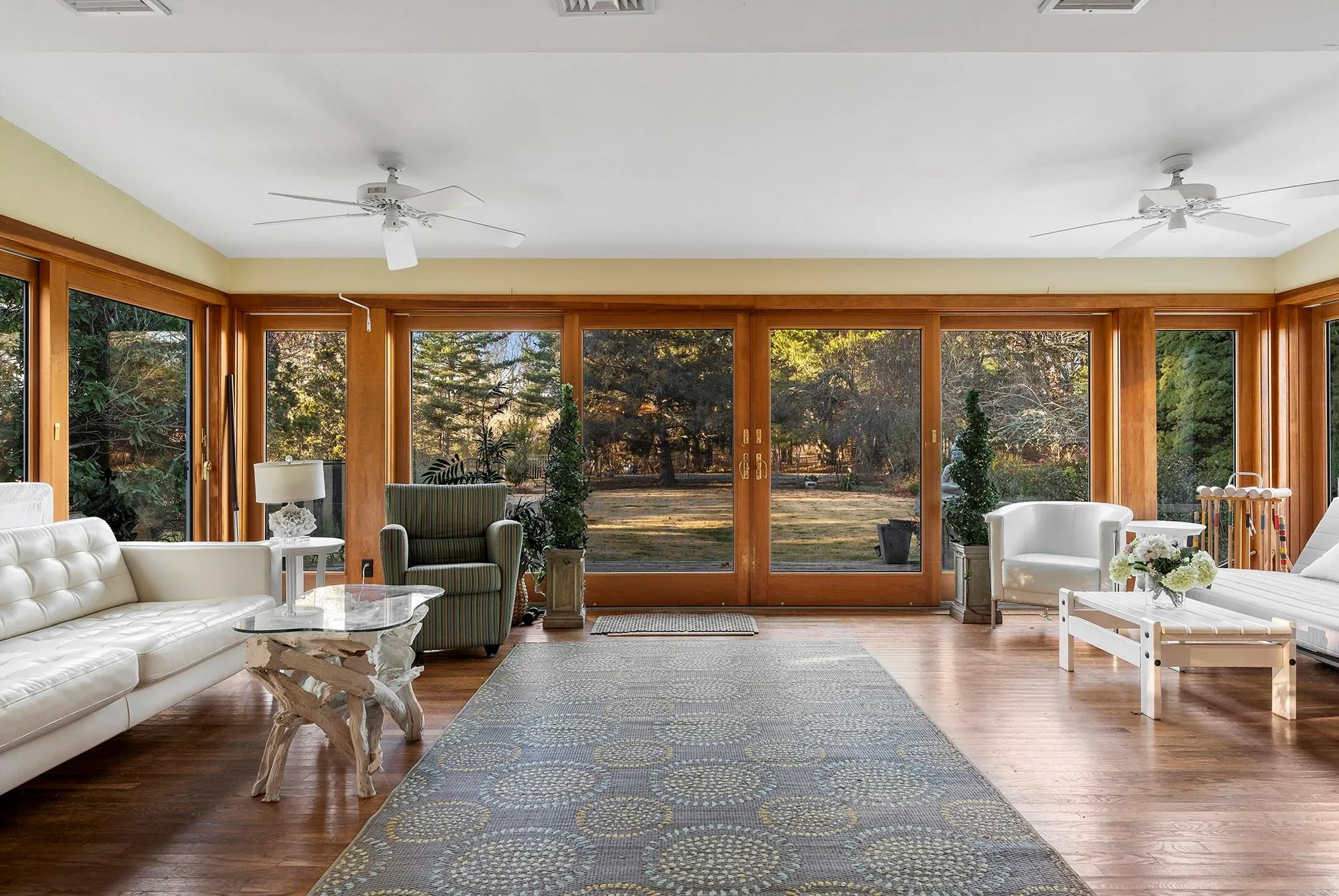 Sunroom with plenty of natural light, wood finished floors, and view of wooded area Sunroom with plenty of natural light, wood finished floors, and view of wooded area