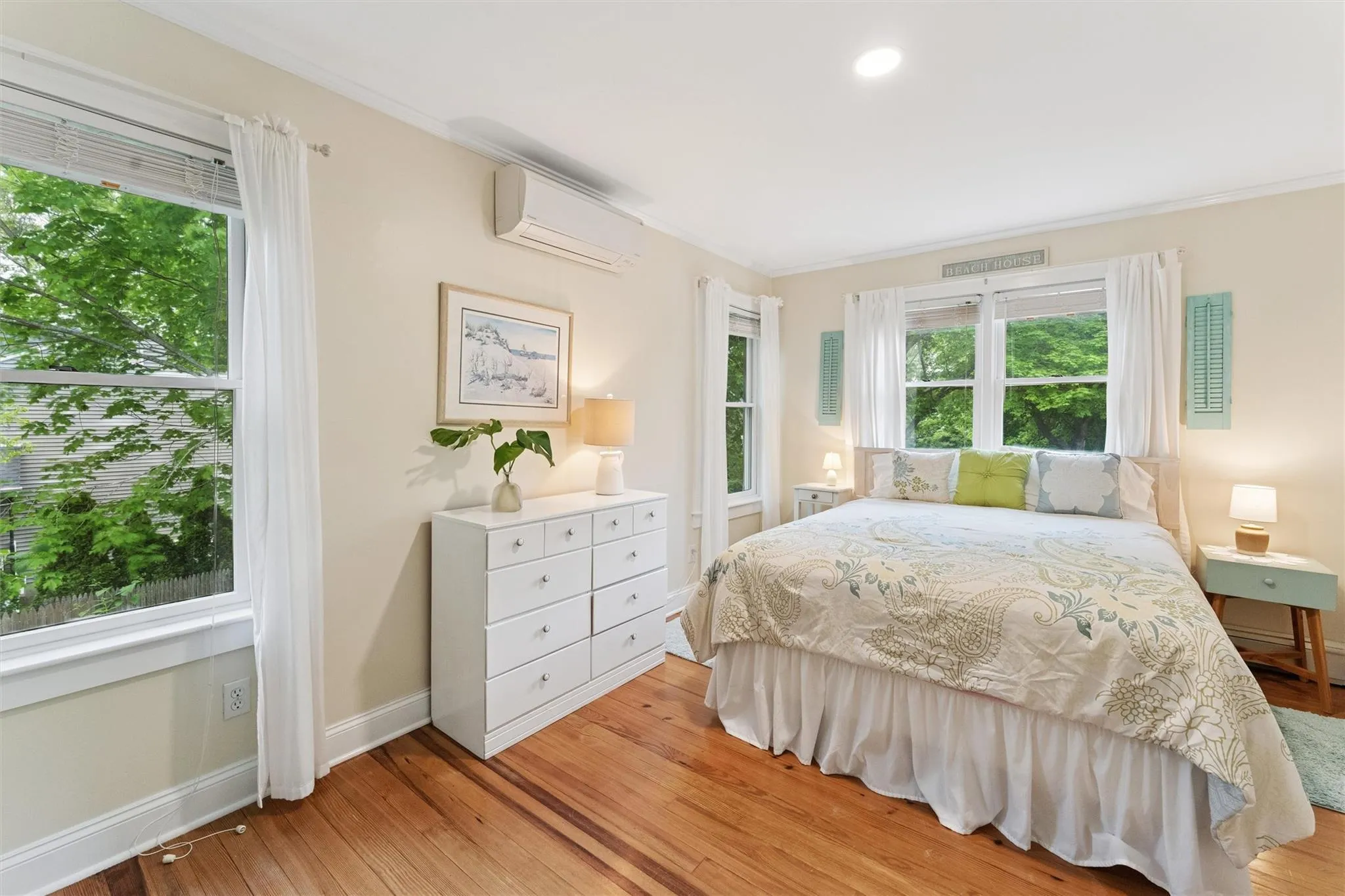 Bedroom with a wall mounted air conditioner, multiple windows, light wood-type flooring, ornamental molding, and recessed lighting Bedroom with a wall mounted air conditioner, multiple windows, light wood-type flooring, ornamental molding, and recessed lighting