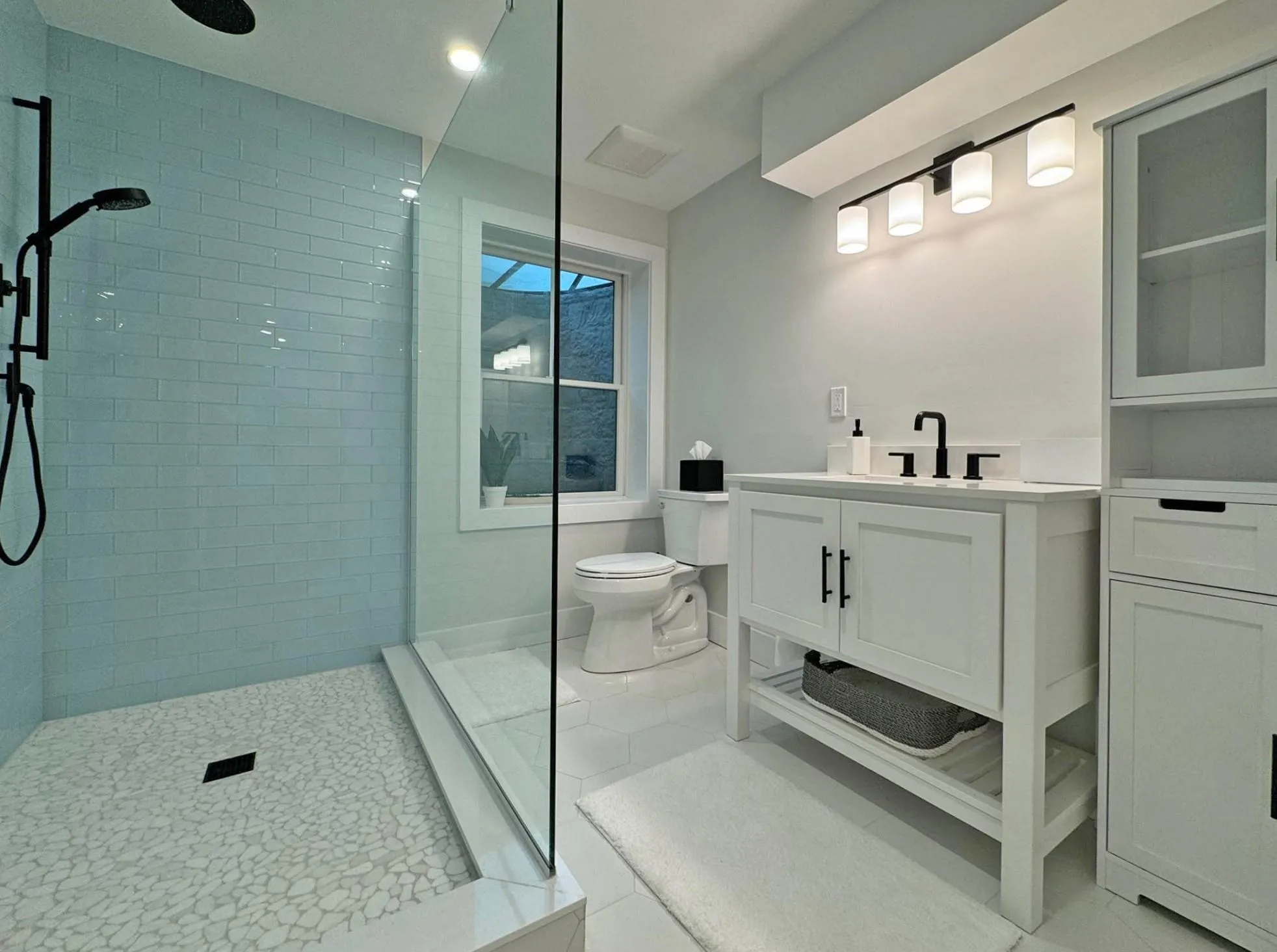 Bathroom with toilet, a tile shower, vanity, and tile patterned floors Bathroom with toilet, a tile shower, vanity, and tile patterned floors