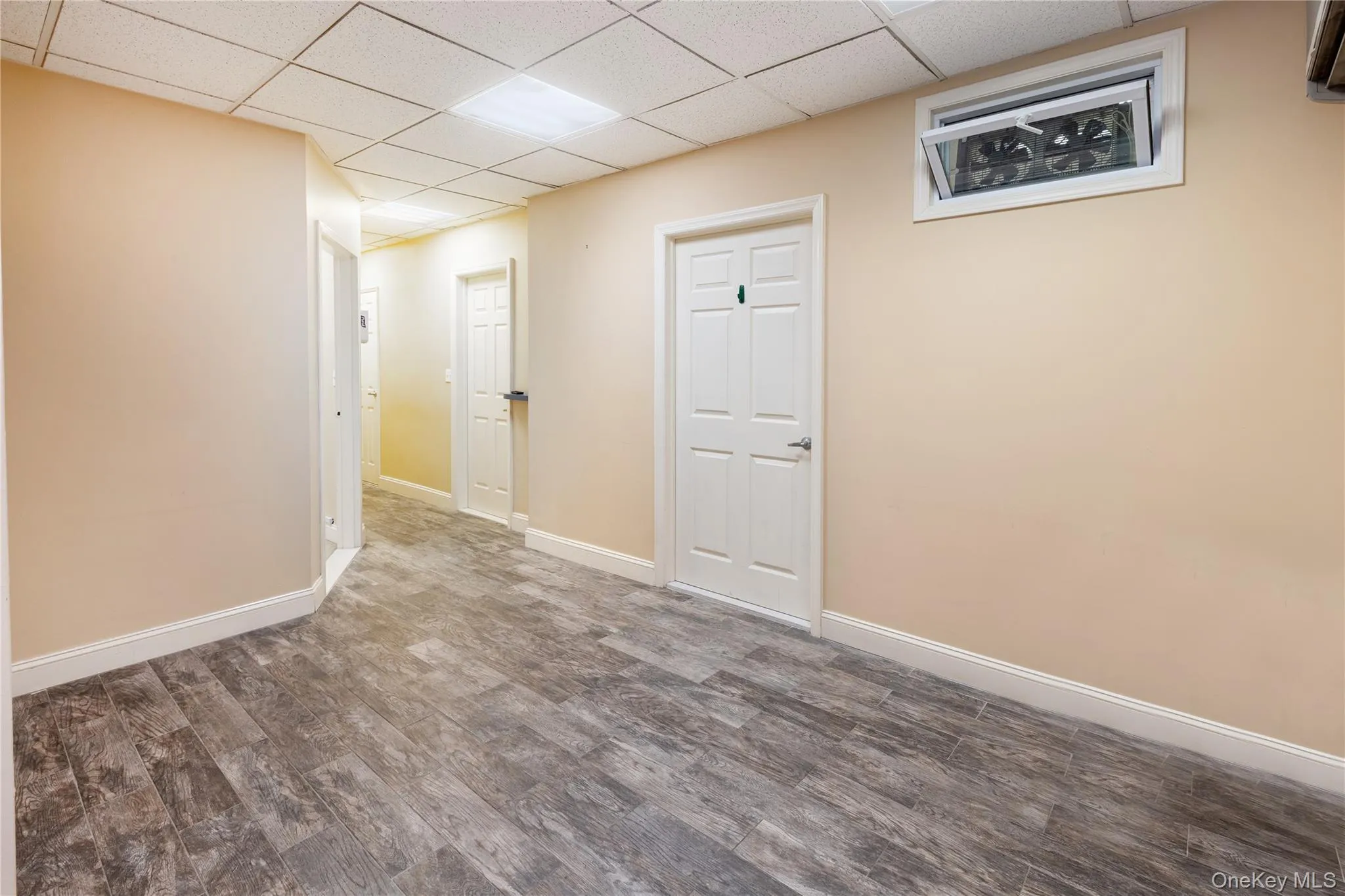 Empty room featuring a drop ceiling and dark hardwood / wood-style floors Empty room featuring a drop ceiling and dark hardwood / wood-style floors