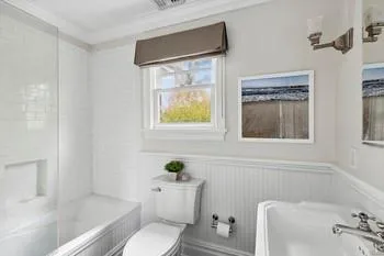 Bathroom with toilet, tiled shower / bath, and ornamental molding