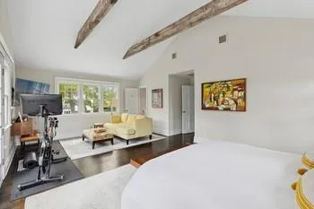 Bedroom with beamed ceiling, hardwood / wood-style floors, and high vaulted ceiling