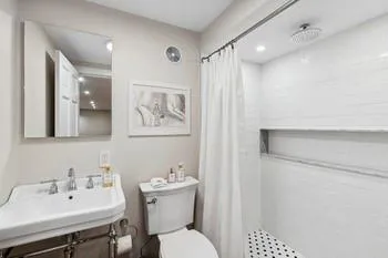 Bathroom with a shower with curtain, sink, and toilet