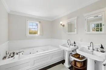 Bathroom with a washtub, dual sinks, and ornamental molding