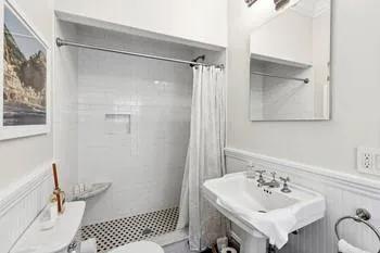 Bathroom with a shower with shower curtain, toilet, and sink