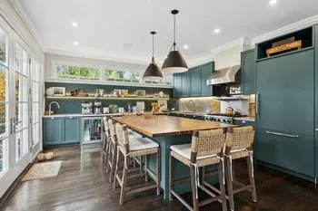 Kitchen featuring wall chimney exhaust hood, ornamental molding, decorative light fixtures, and a kitchen island