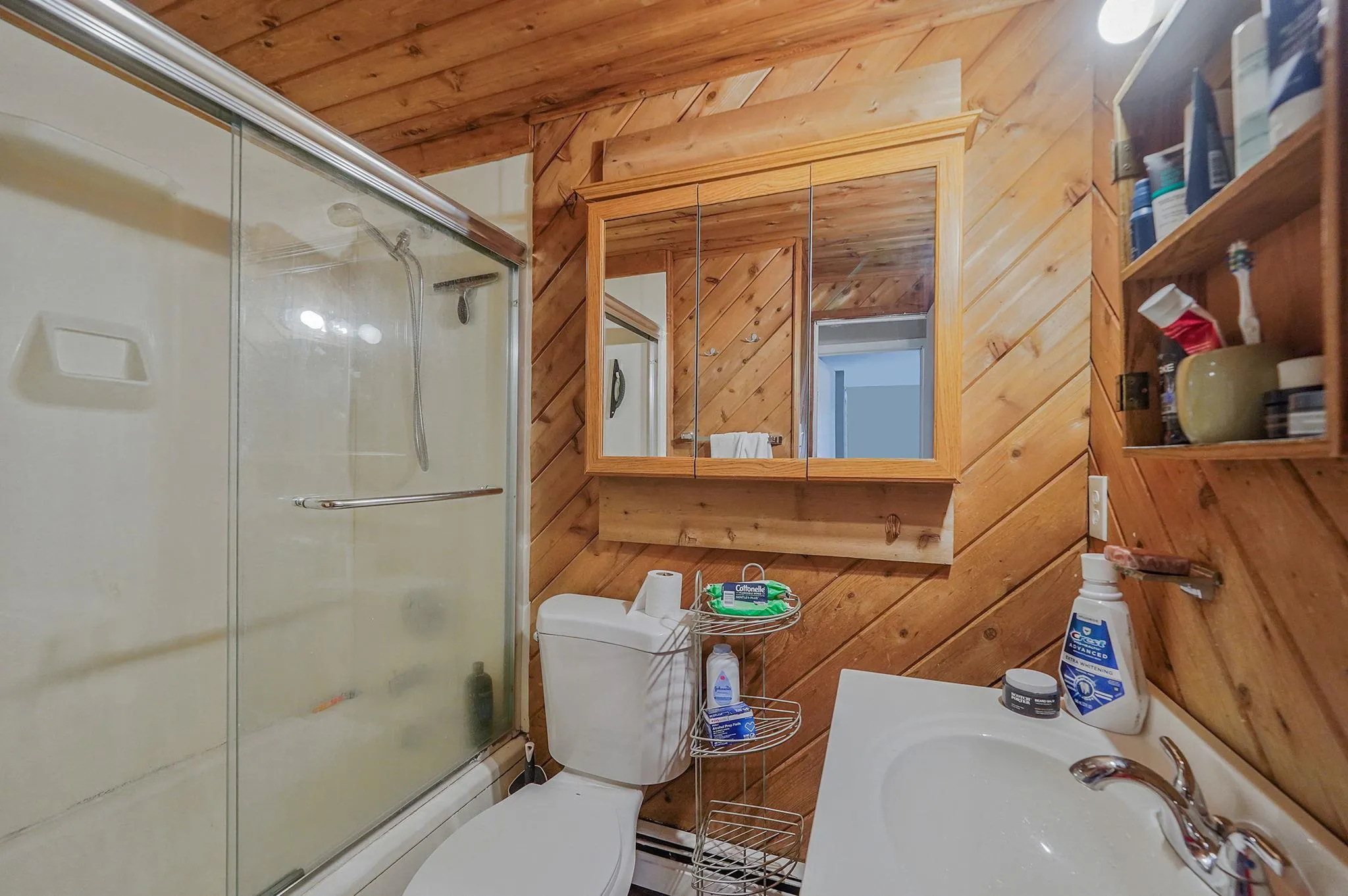 Full bathroom featuring wooden walls, wooden ceiling, vanity, and shower / bath combination with glass door Full bathroom featuring wooden walls, wooden ceiling, vanity, and shower / bath combination with glass door
