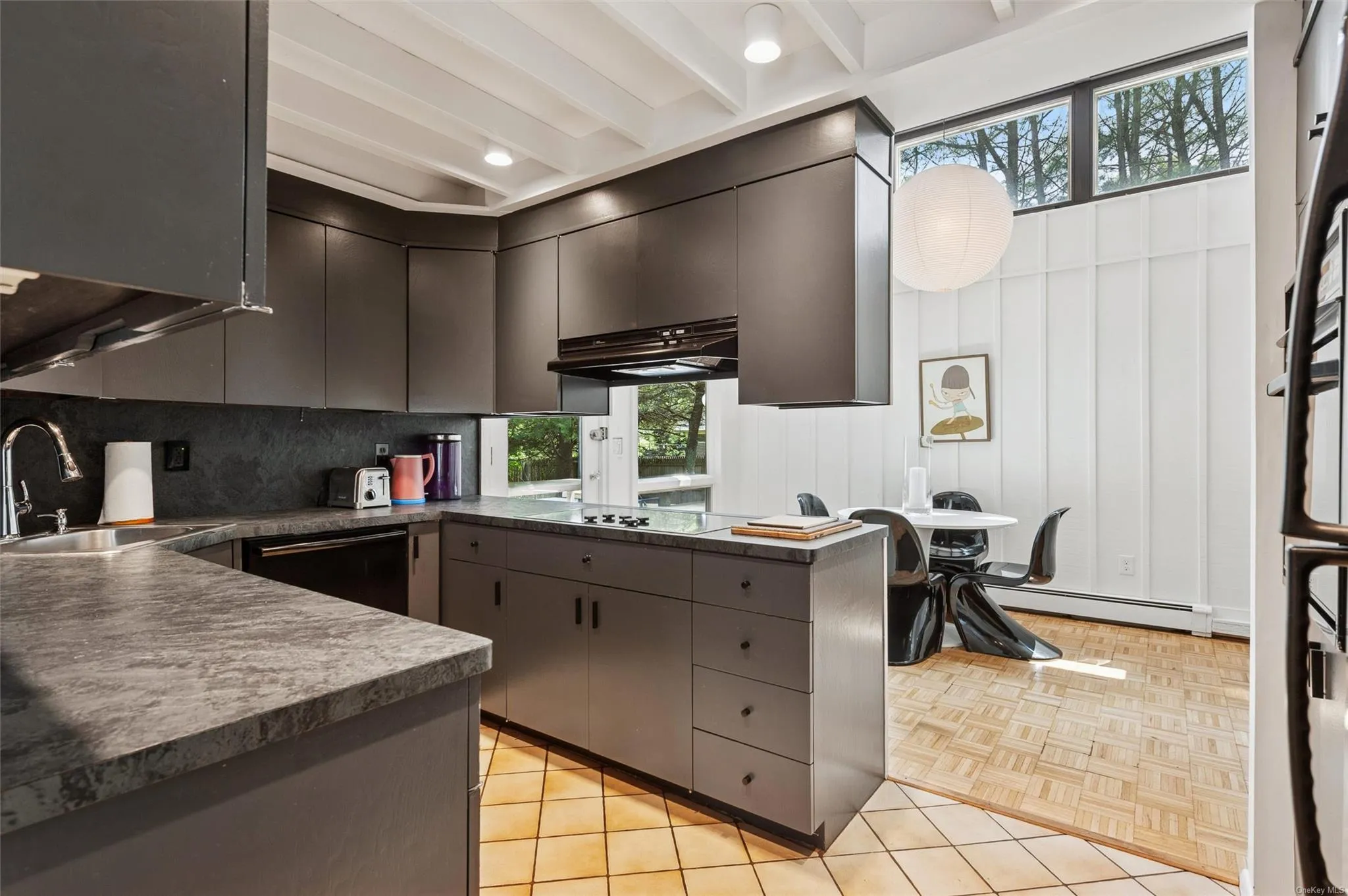 Kitchen with a sink, dark countertops, a baseboard heating unit, range hood, and tasteful backsplash Kitchen with a sink, dark countertops, a baseboard heating unit, range hood, and tasteful backsplash
