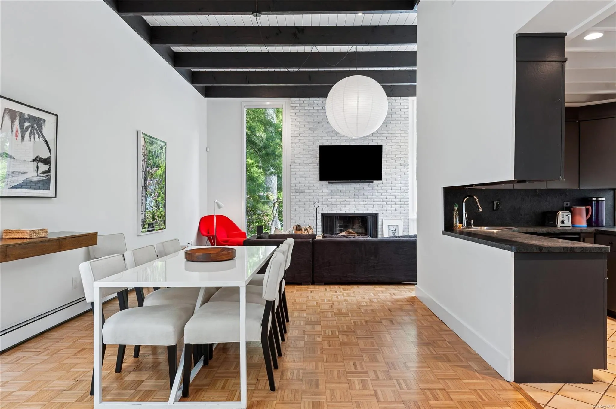 Dining area featuring beam ceiling, a brick fireplace, and baseboards Dining area featuring beam ceiling, a brick fireplace, and baseboards