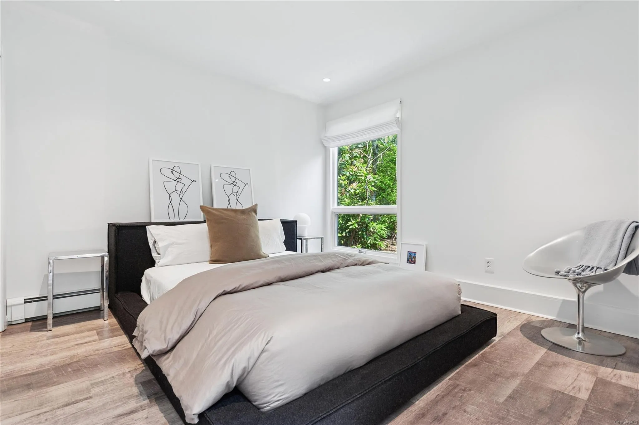 Bedroom featuring a baseboard heating unit, light wood-style floors, and baseboards Bedroom featuring a baseboard heating unit, light wood-style floors, and baseboards