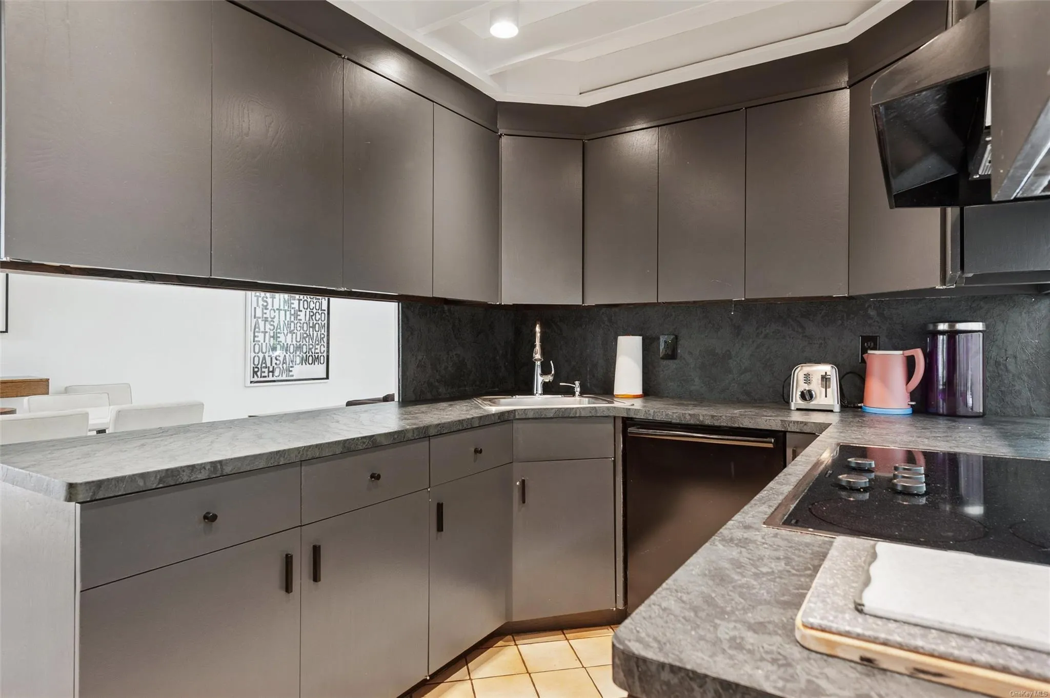 Kitchen featuring black electric stovetop, tasteful backsplash, a sink, and gray cabinetry Kitchen featuring black electric stovetop, tasteful backsplash, a sink, and gray cabinetry