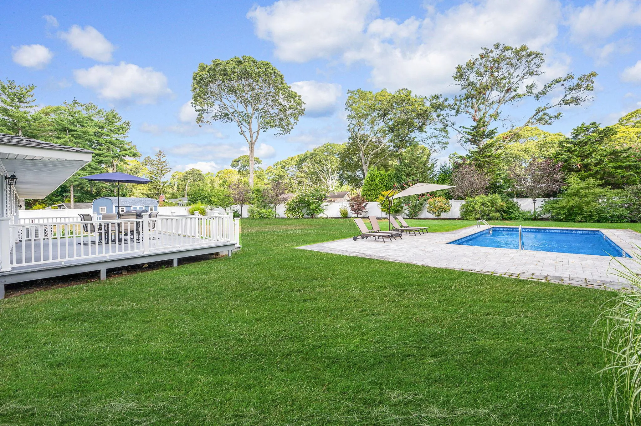 Fenced backyard with a wooden deck and a patio area Fenced backyard with a wooden deck and a patio area