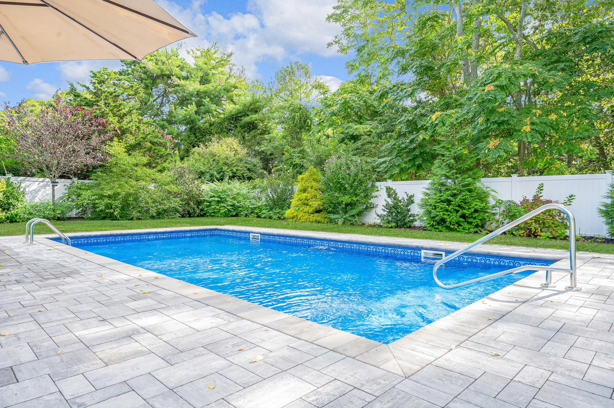 View of pool with a fenced backyard, a patio area, and view of wooded area View of pool with a fenced backyard, a patio area, and view of wooded area