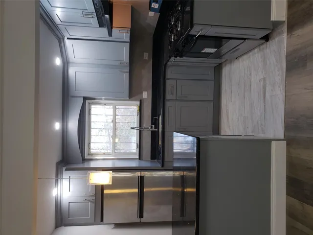 Kitchen featuring sink, ventilation hood, decorative light fixtures, fridge, and range