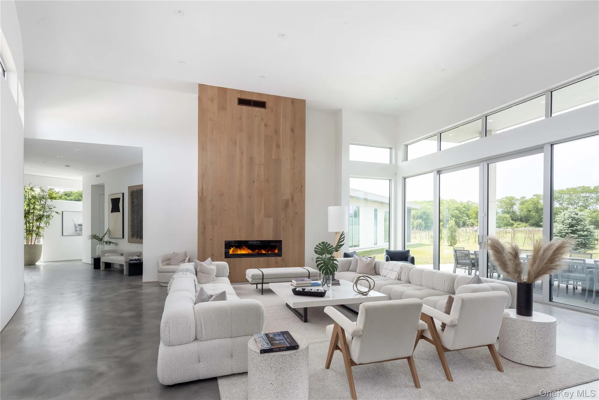 Living room with a large fireplace, a high ceiling, and concrete floors Living room with a large fireplace, a high ceiling, and concrete floors