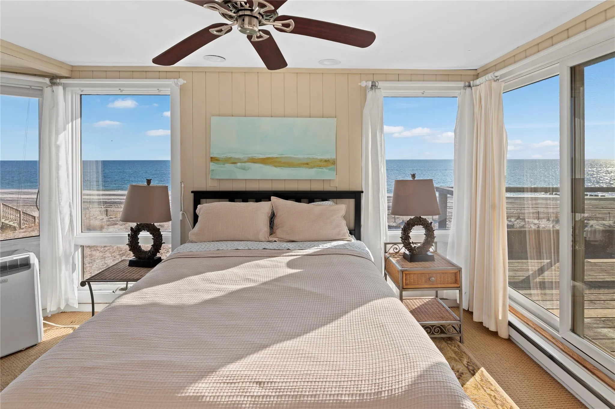 Bedroom with a water view, wooden walls, ceiling fan, baseboard heating, and light colored carpet Bedroom with a water view, wooden walls, ceiling fan, baseboard heating, and light colored carpet
