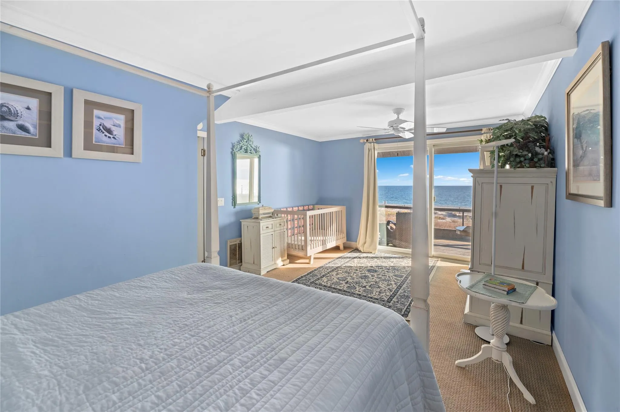 Bedroom featuring beam ceiling, ceiling fan, light colored carpet, a water view, and ornamental molding Bedroom featuring beam ceiling, ceiling fan, light colored carpet, a water view, and ornamental molding