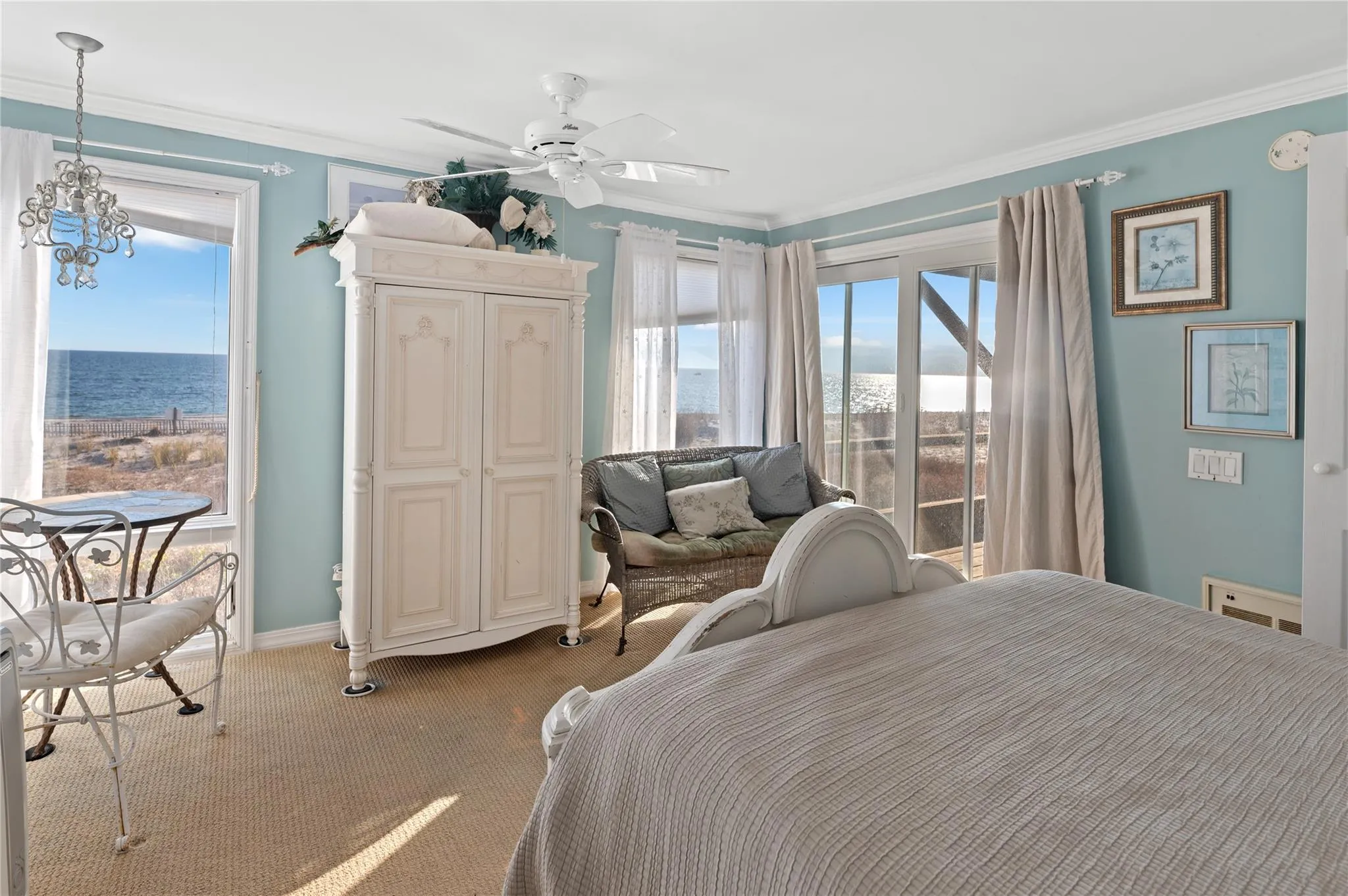Carpeted bedroom featuring ceiling fan with notable chandelier, a water view, ornamental molding, and multiple windows Carpeted bedroom featuring ceiling fan with notable chandelier, a water view, ornamental molding, and multiple windows
