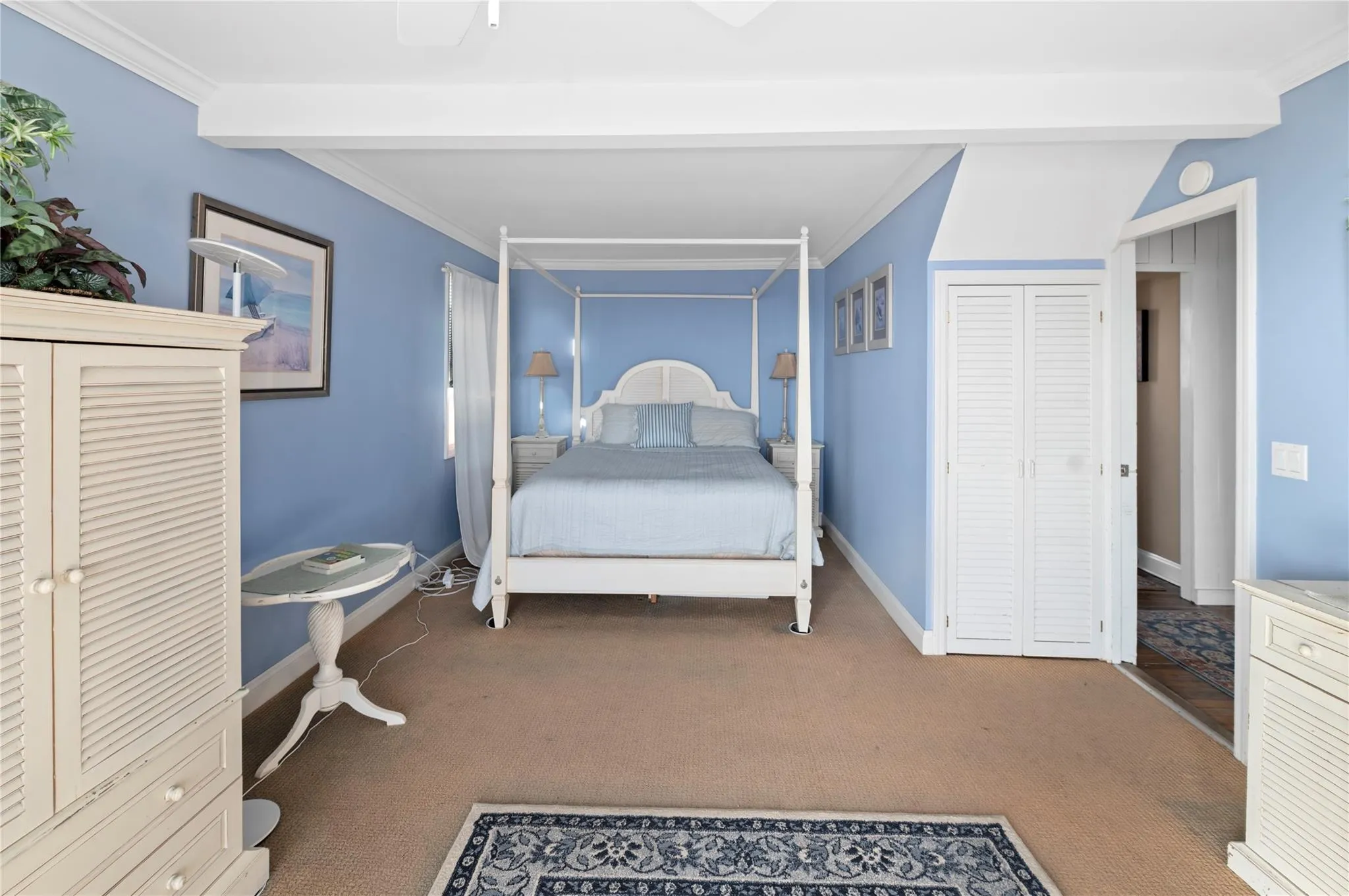 Carpeted bedroom with ceiling fan, beam ceiling, crown molding, and a closet Carpeted bedroom with ceiling fan, beam ceiling, crown molding, and a closet