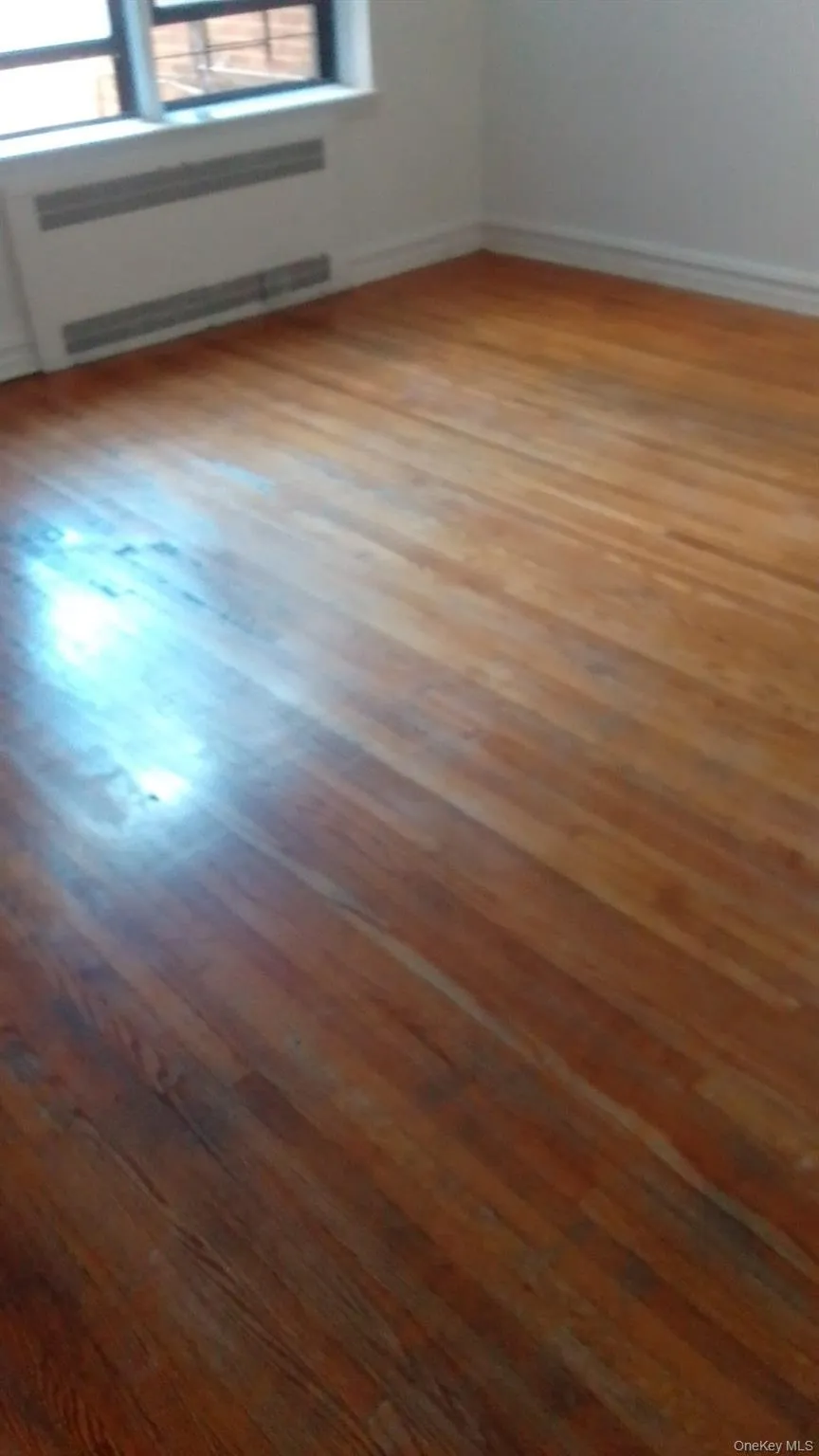 Spare room with wood-type flooring and a baseboard heating unit Spare room with wood-type flooring and a baseboard heating unit