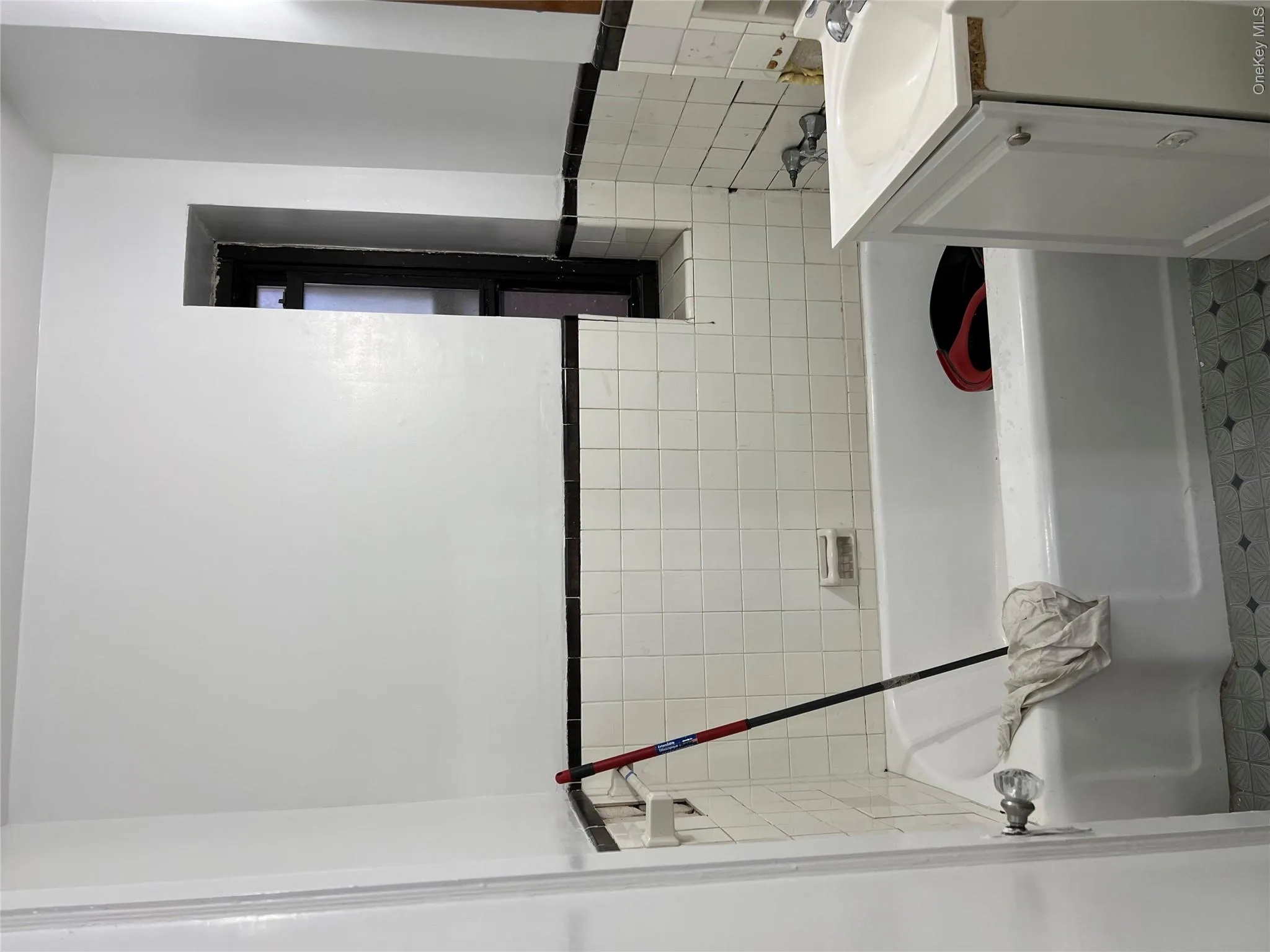 Bathroom featuring a bathtub, vanity, and tile walls Bathroom featuring a bathtub, vanity, and tile walls