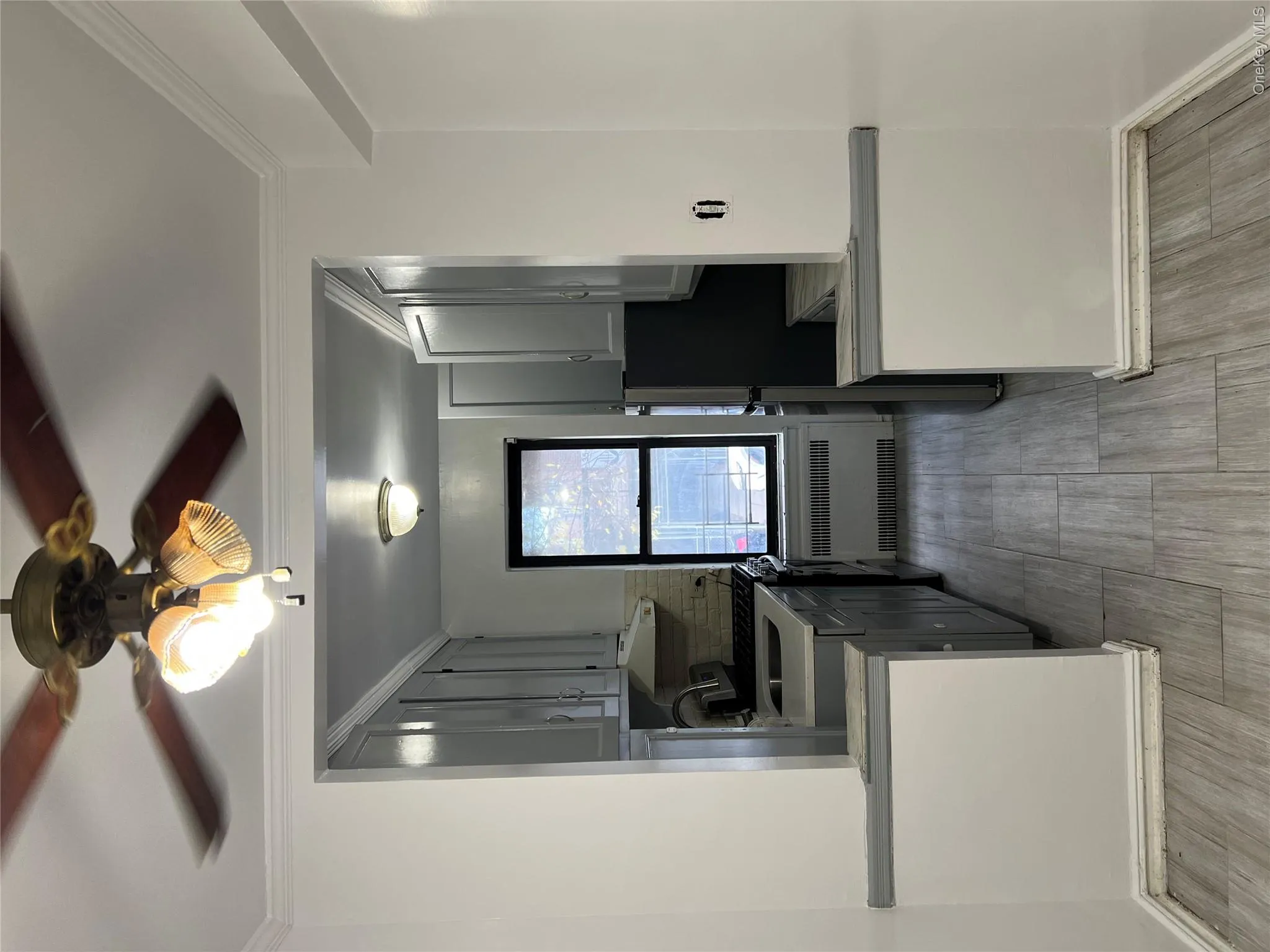 Kitchen with gray cabinetry, radiator, crown molding, ceiling fan, and tasteful backsplash Kitchen with gray cabinetry, radiator, crown molding, ceiling fan, and tasteful backsplash